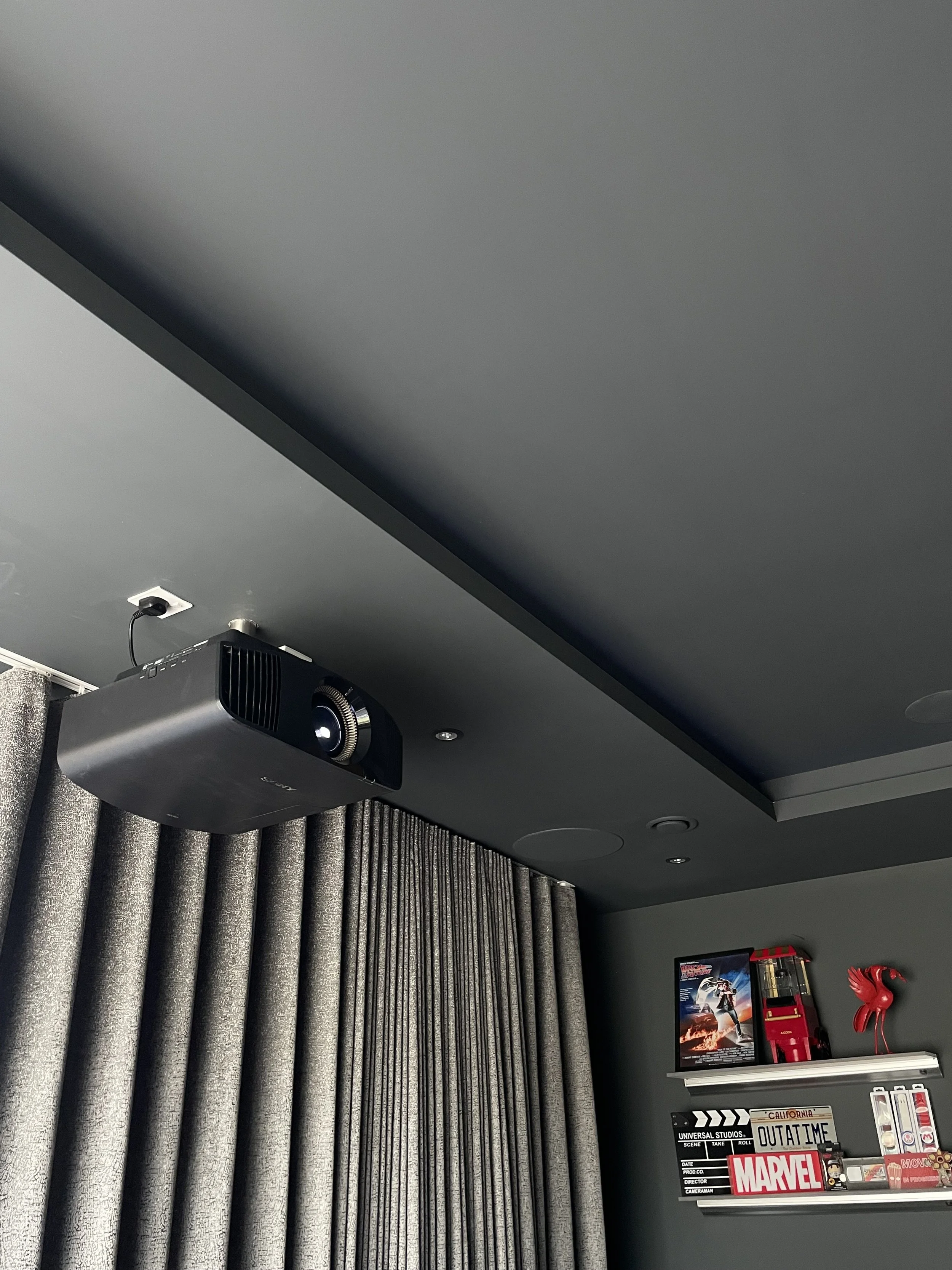 A black ceiling-mounted home cinema projector