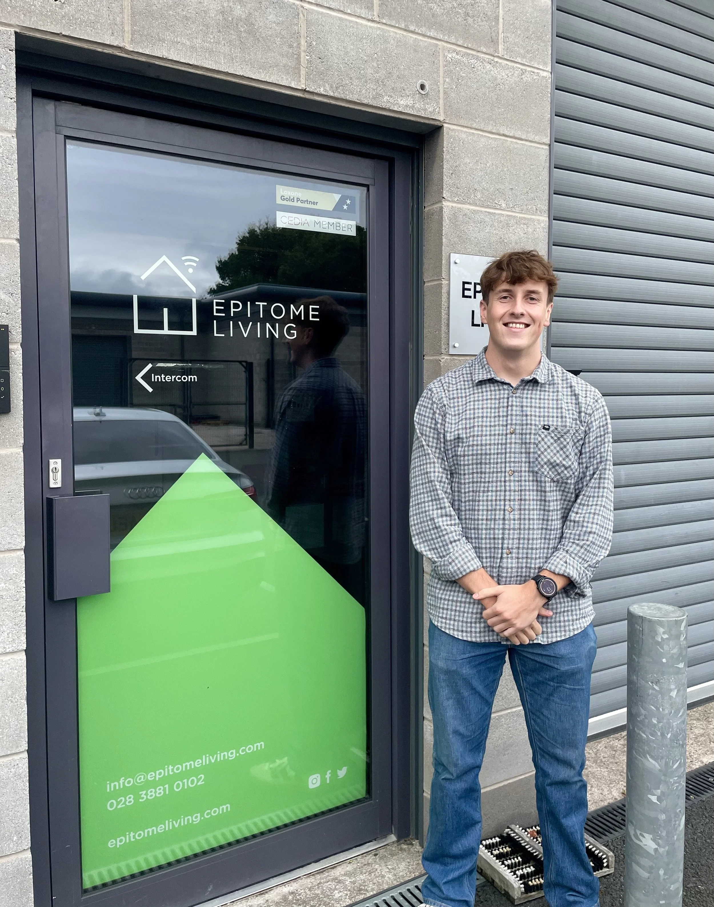 An Epitome Living team member stands by the branded green & grey office door 
