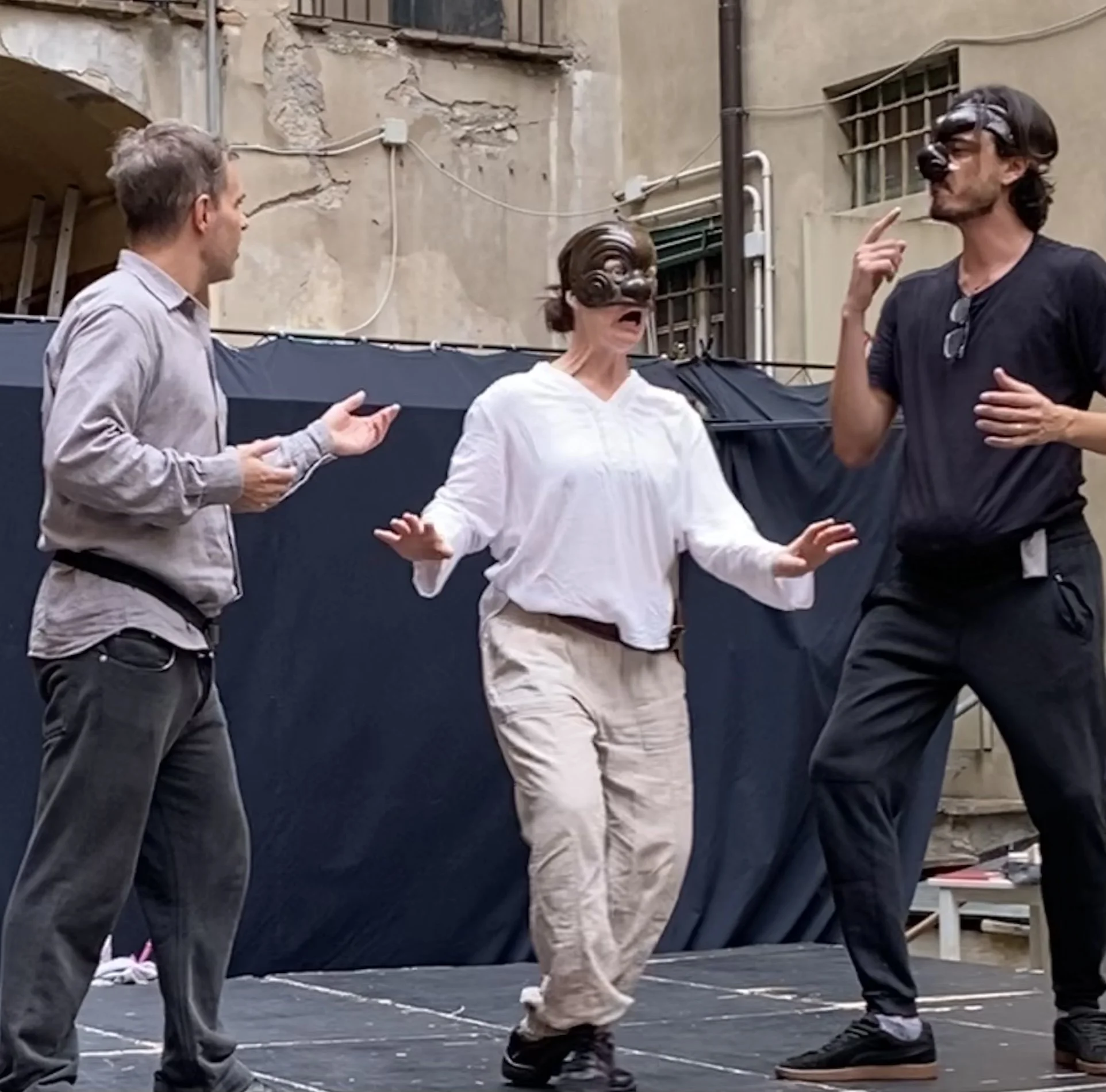 three actors in a scene, two in masks
