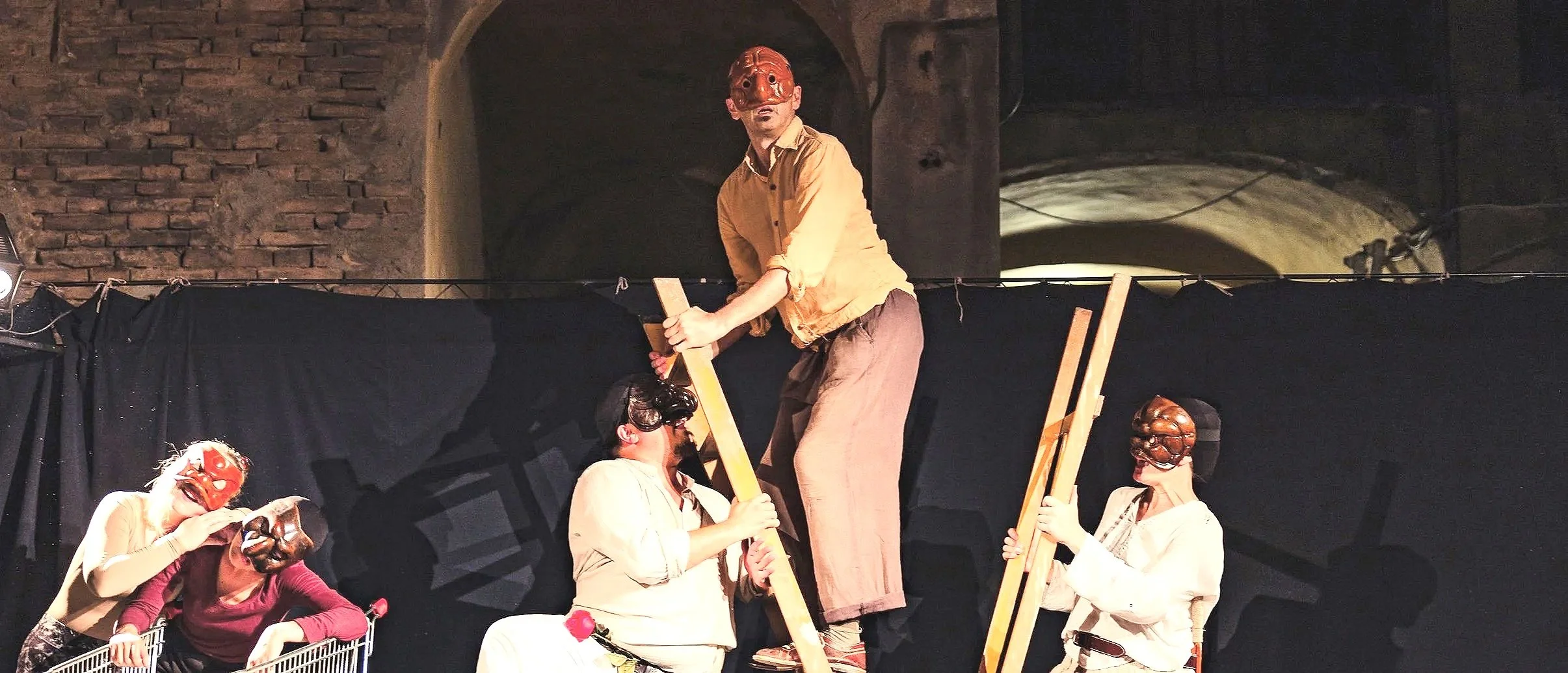 five masked actors, one stood on an upside down ladder held by two others