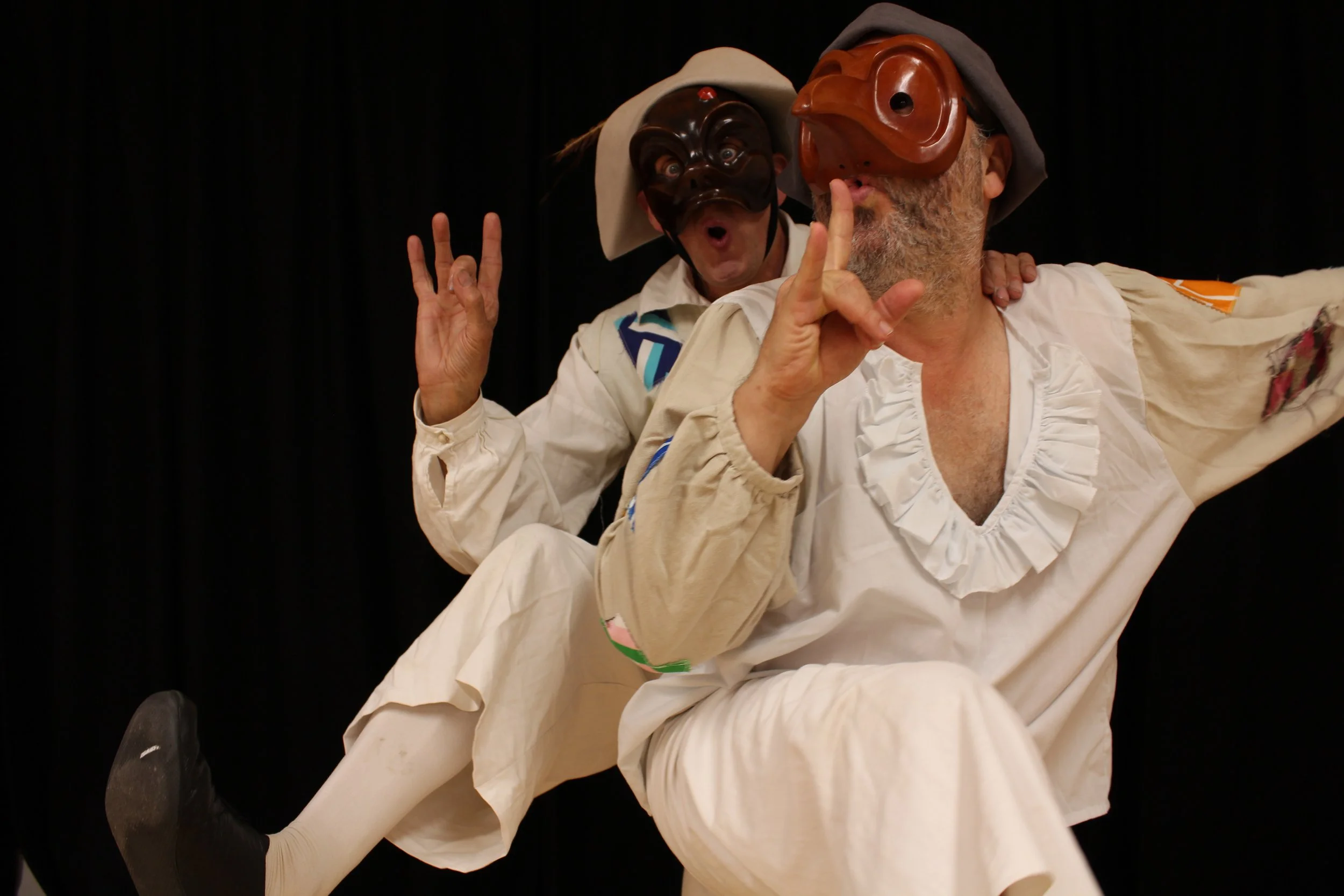 two masked, costumed actors creeping together