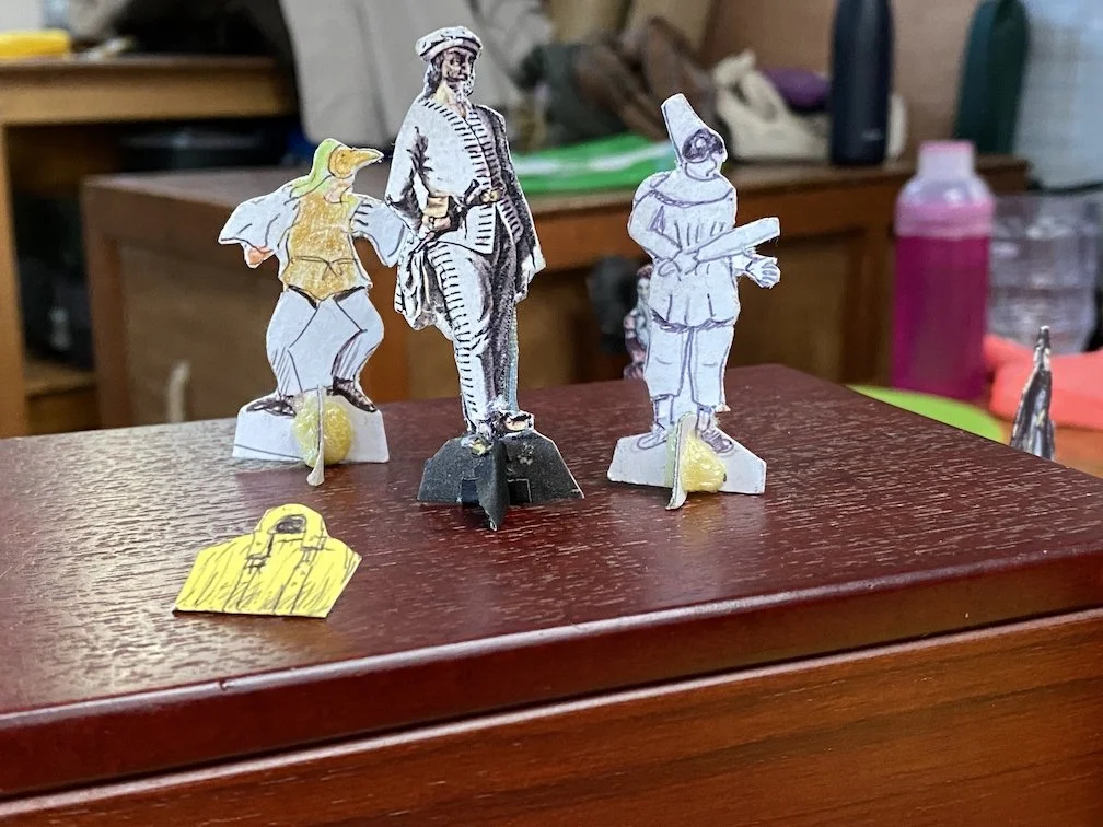 miniature freestanding pictures of three commedia characters and a bag