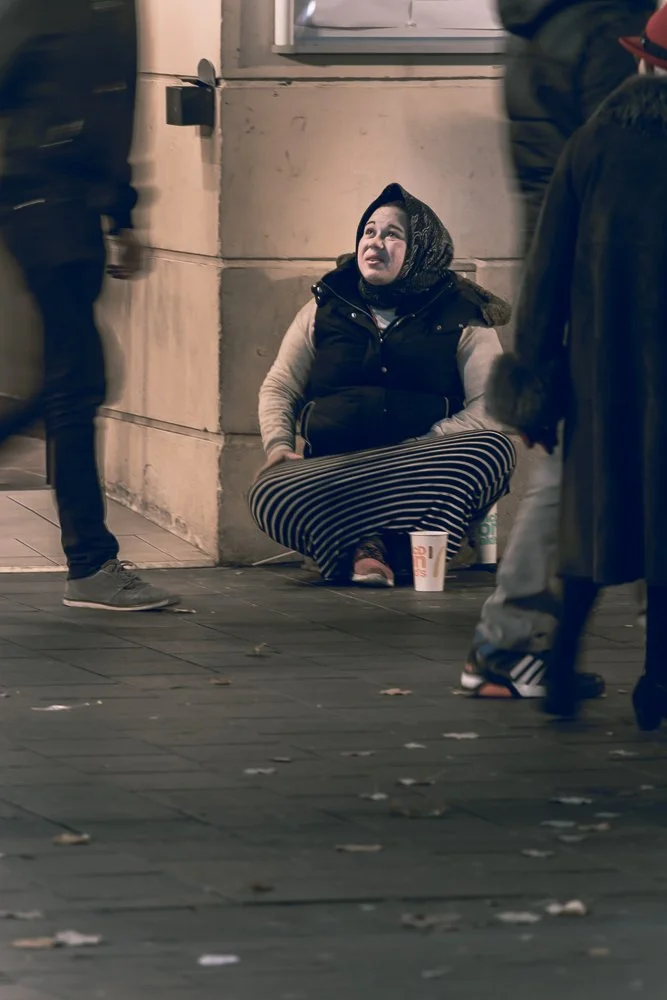 A woman seated beside a busy city walkway