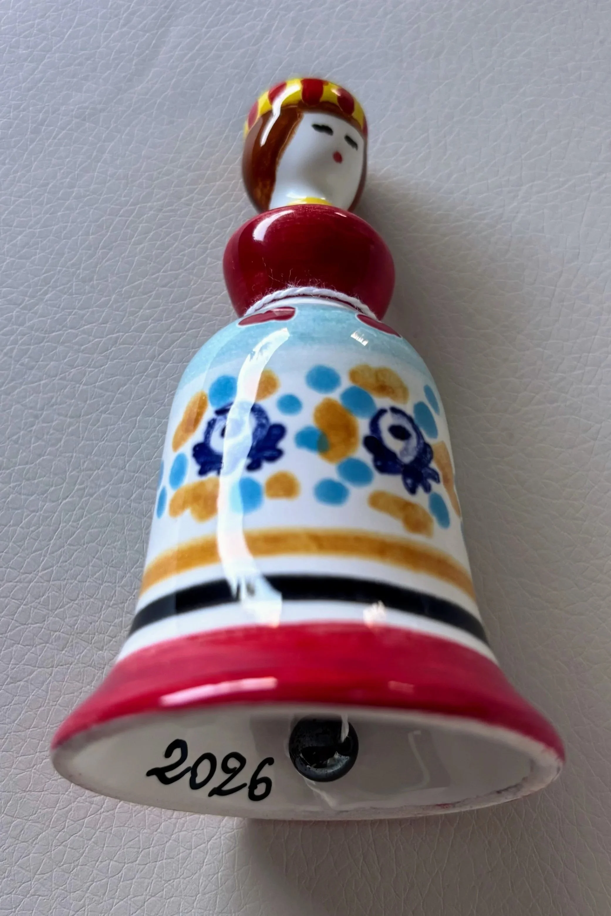 A little ceramic bell the shape of a woman, with the year 2026 written inside it
