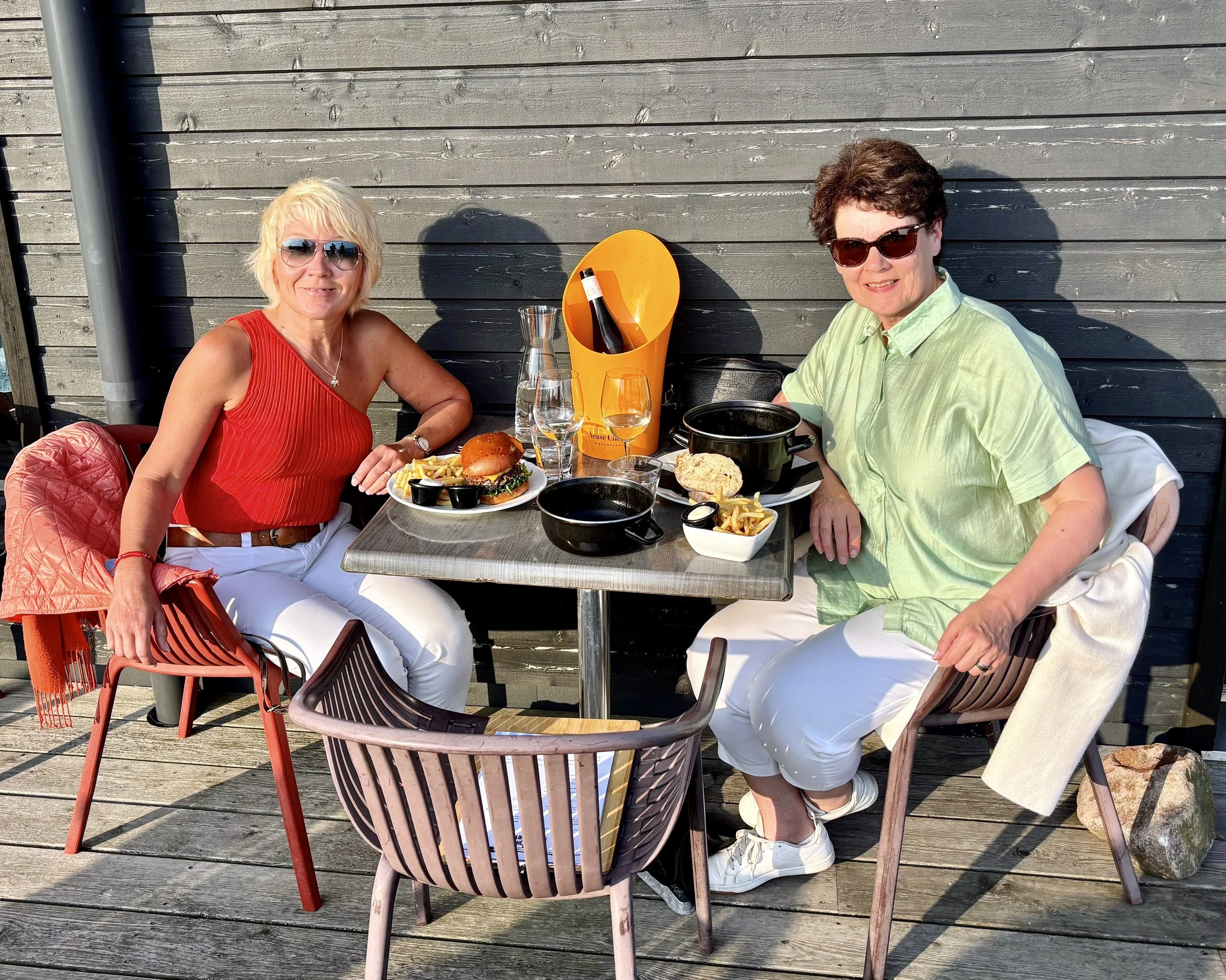 Anita and Mirkka on the terrace of Hangonportti restaurant in Hanko Finland, wearing sunglasses, and dinner food is on the table