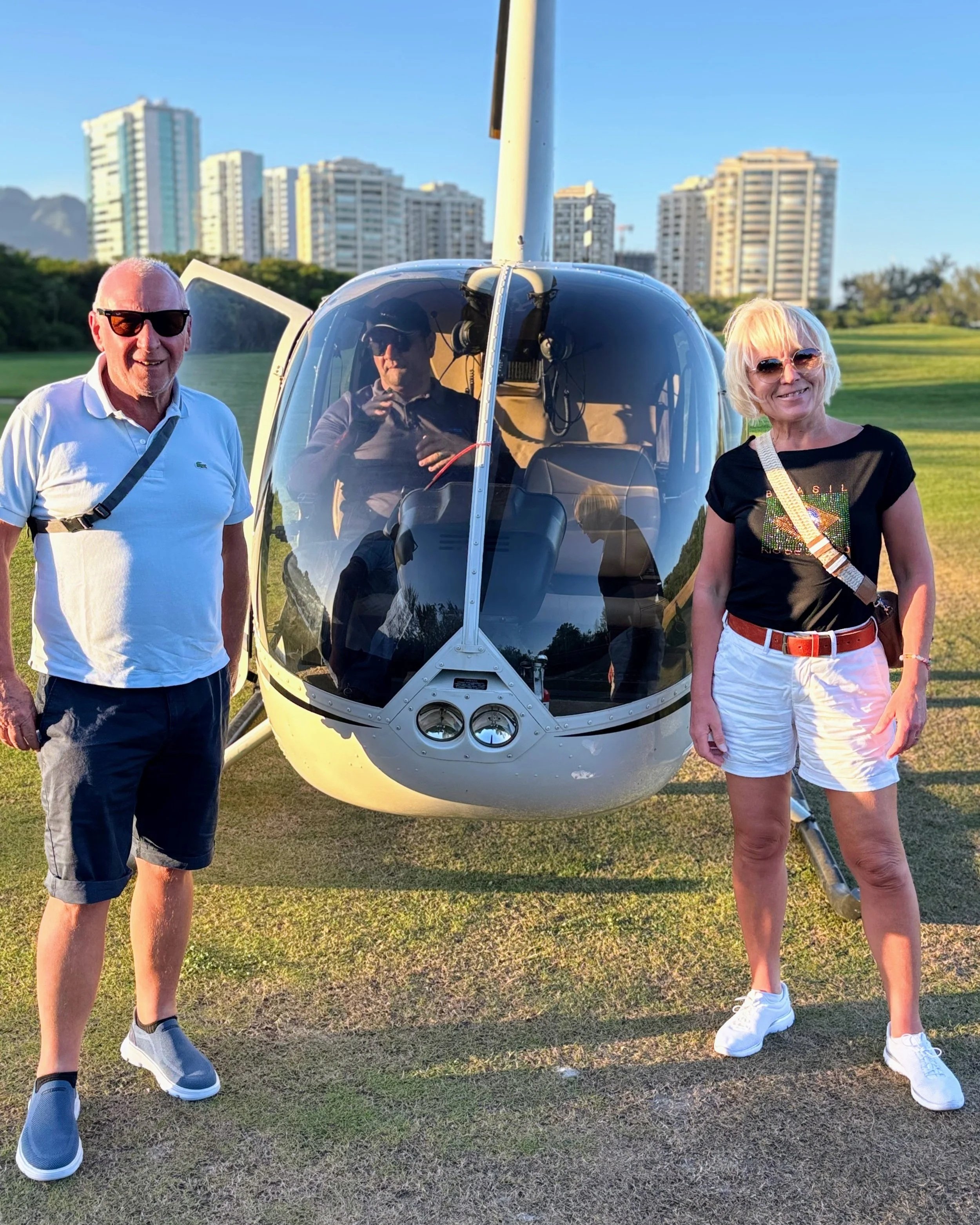 Anita and Umberto standing on both sides of a helicopter, with the pilot sitting inside.