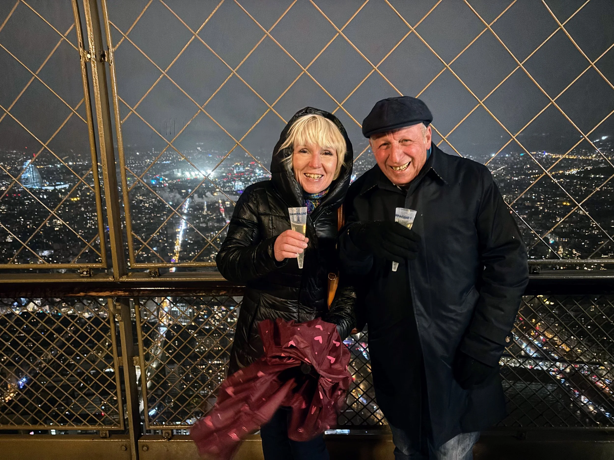Anita and Umberto at top of Eiffel Tower with champagne