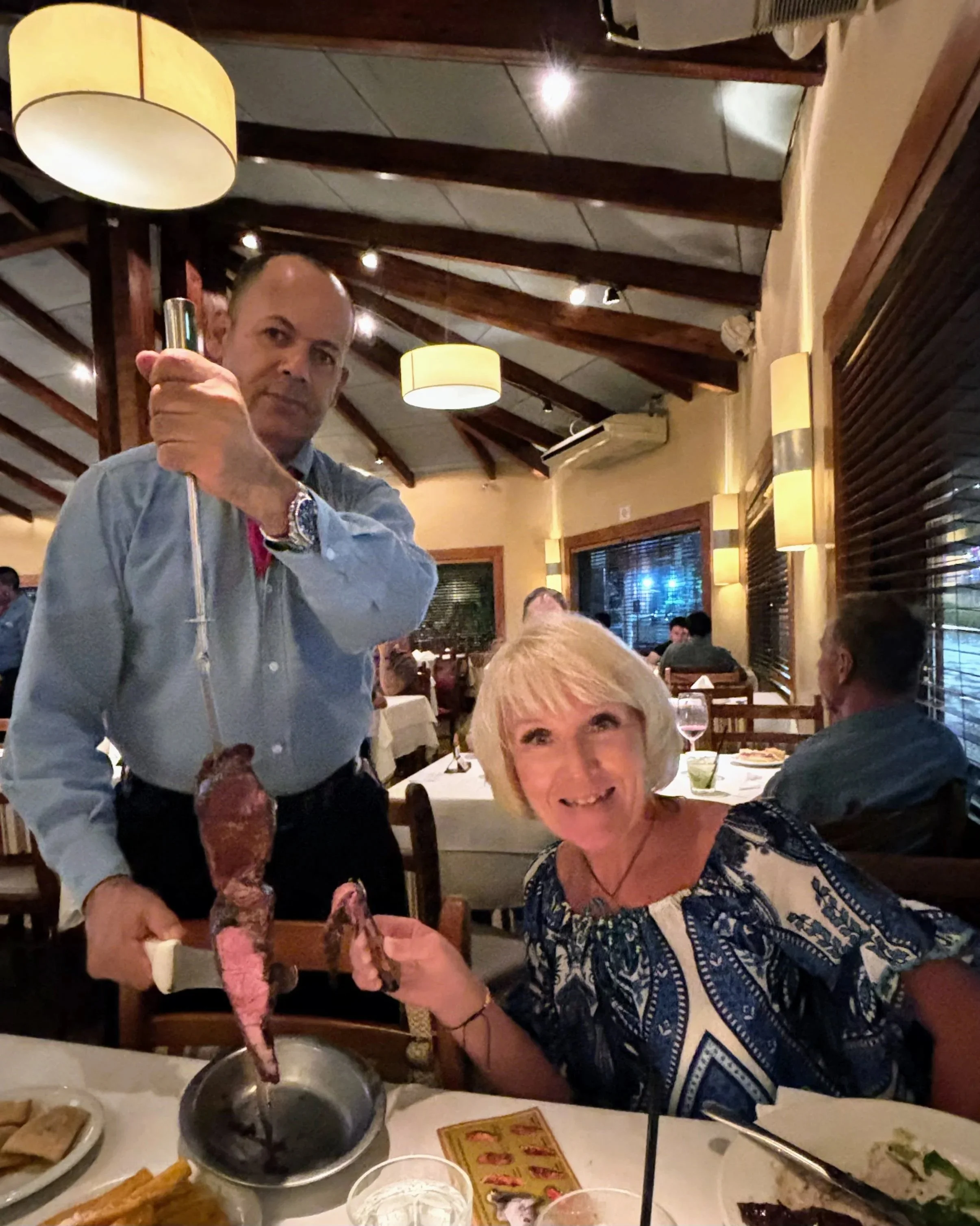 Anita at a Churrascaria in Sao Paulo Brazil with a waiter cutting barbecued meat at the table