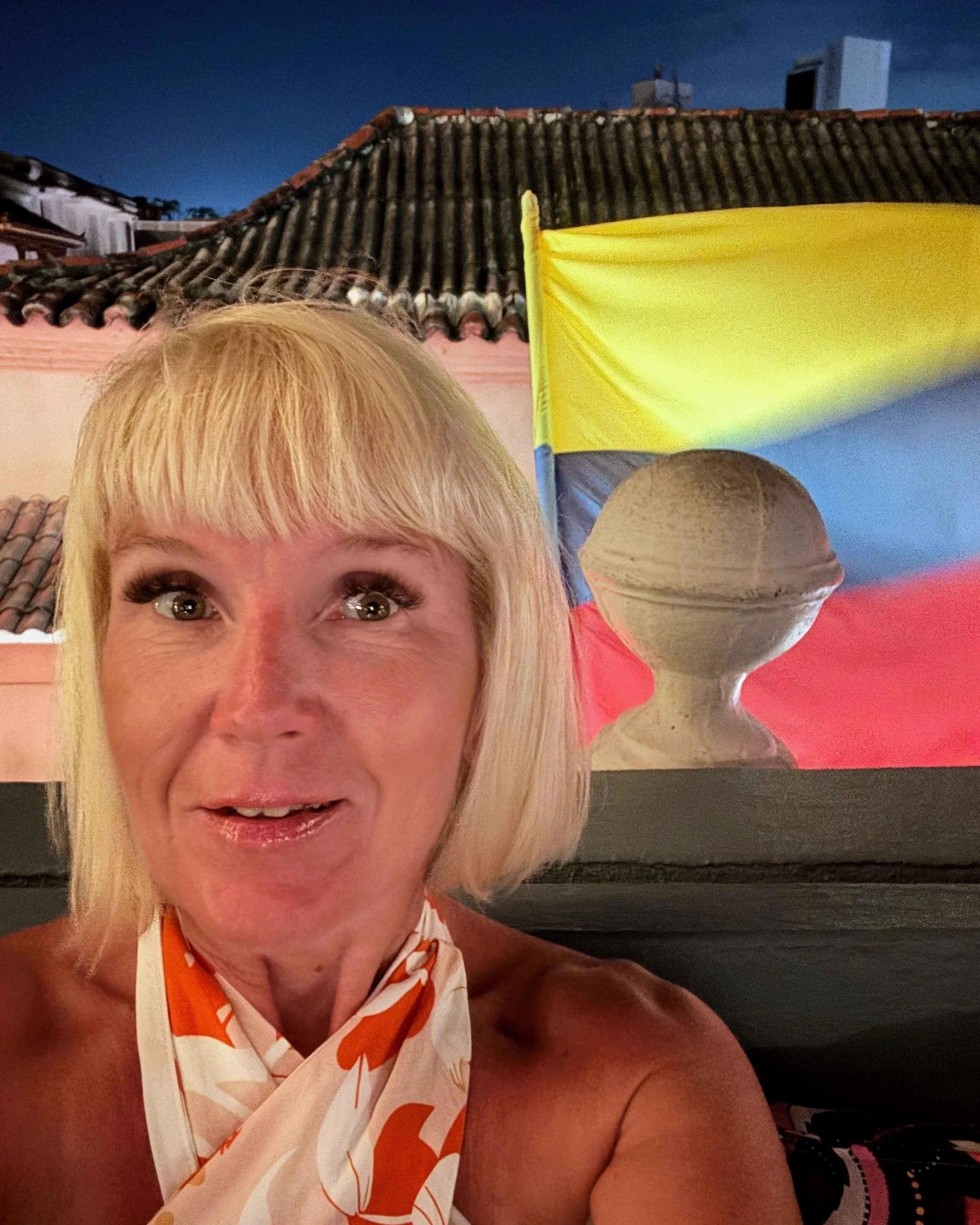 Anita at a rooftop restaurant with colombian flag behind her back