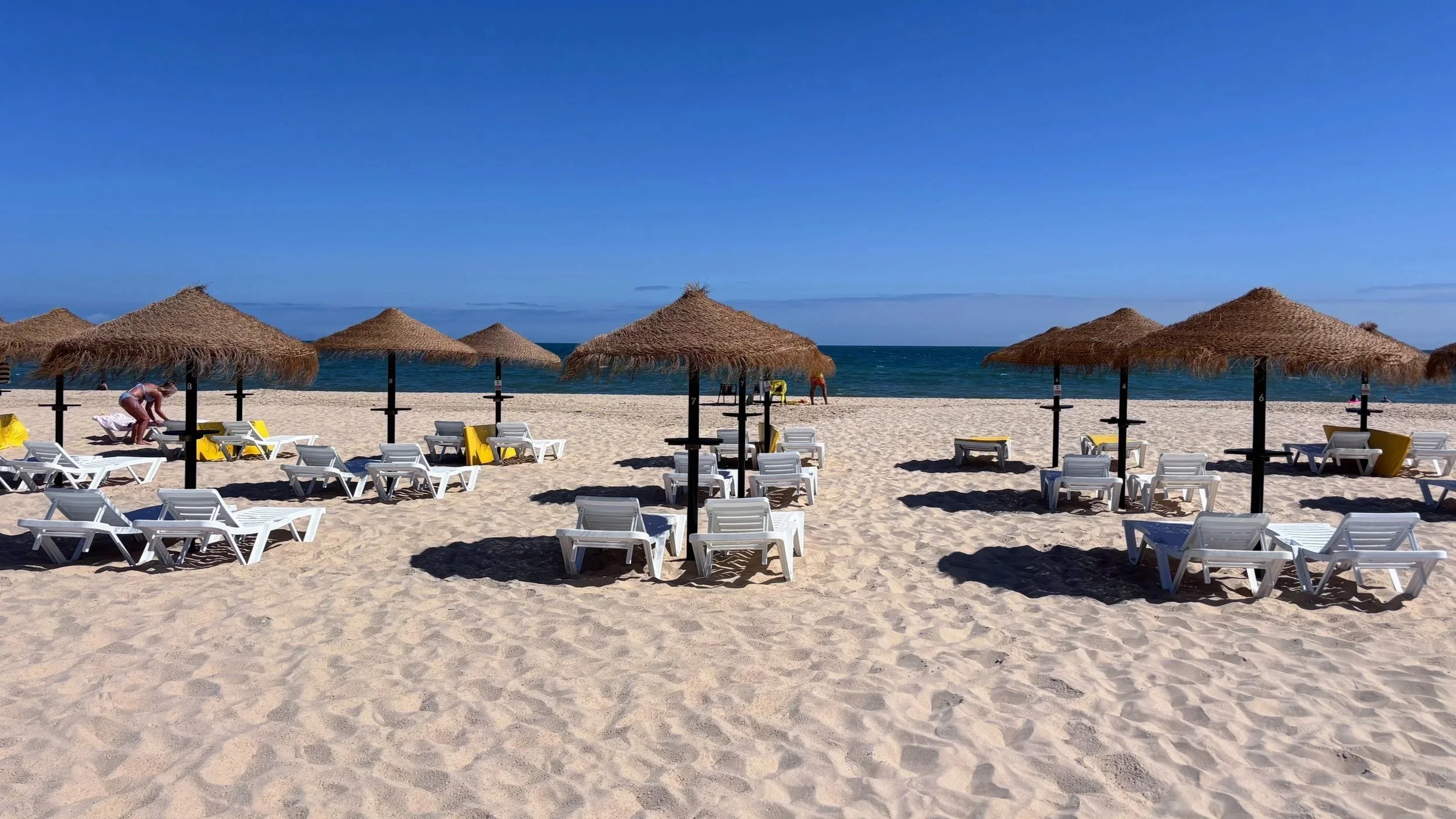 umbrellas and sunbeds on white sand at a beach club in the Algarve in Portugal