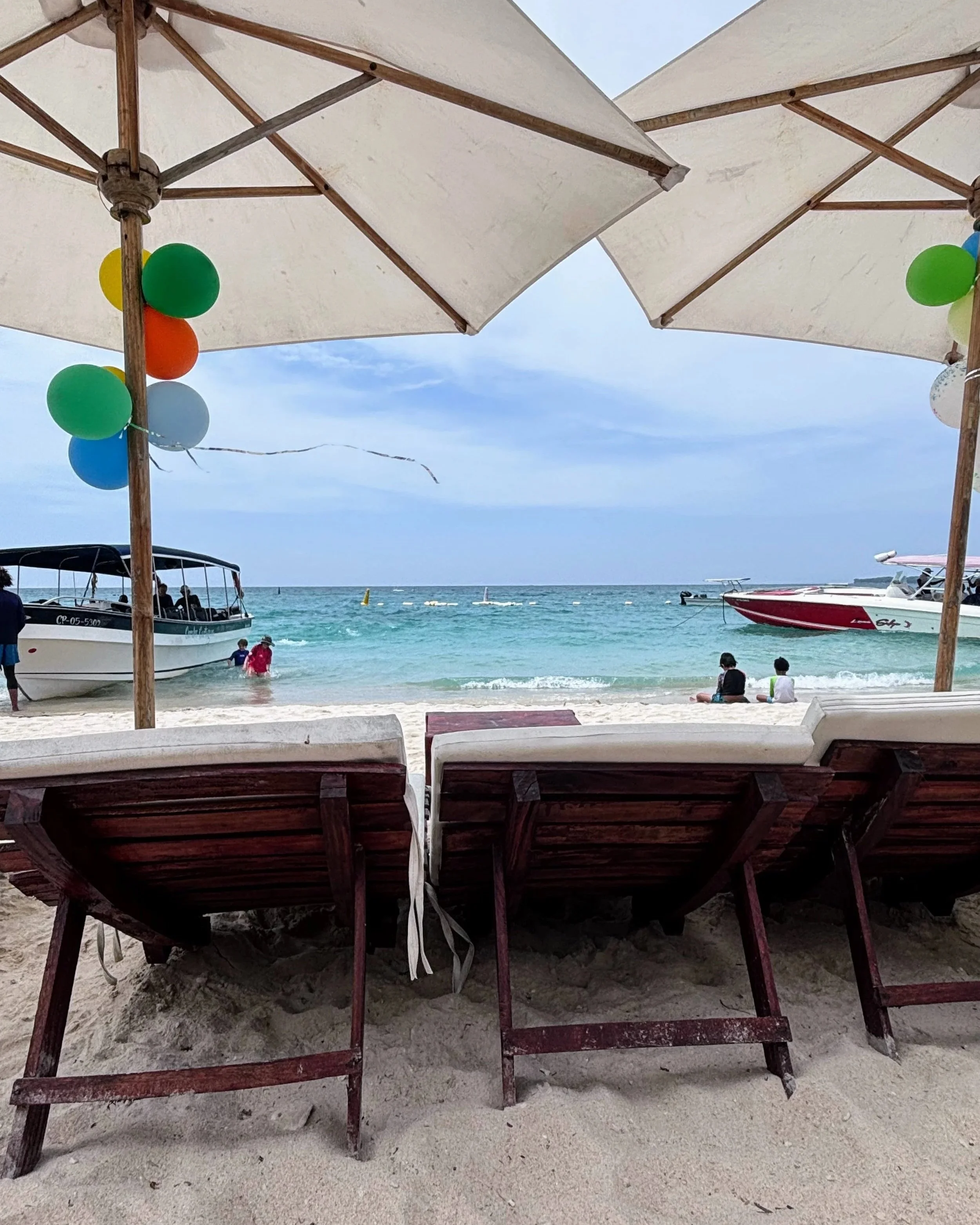 Two white umbrellas on white sand in Playa Blanca, Rosario Islands, Colombia