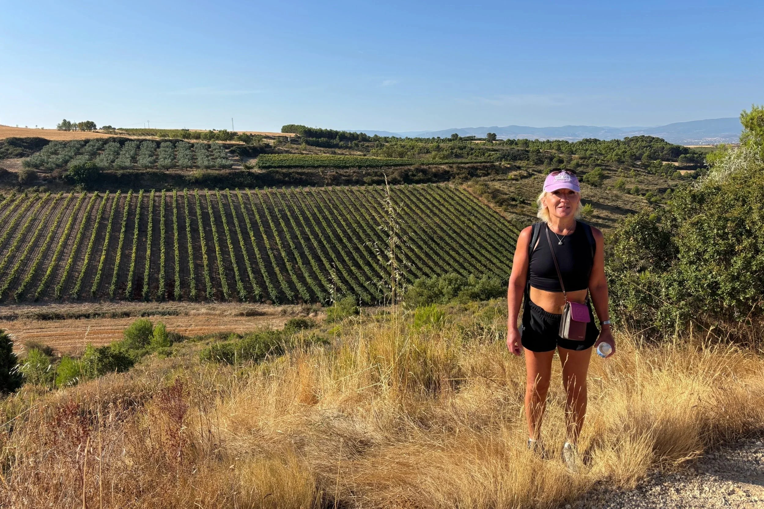 Anita posing with La Rioja vineyards and hills in the background