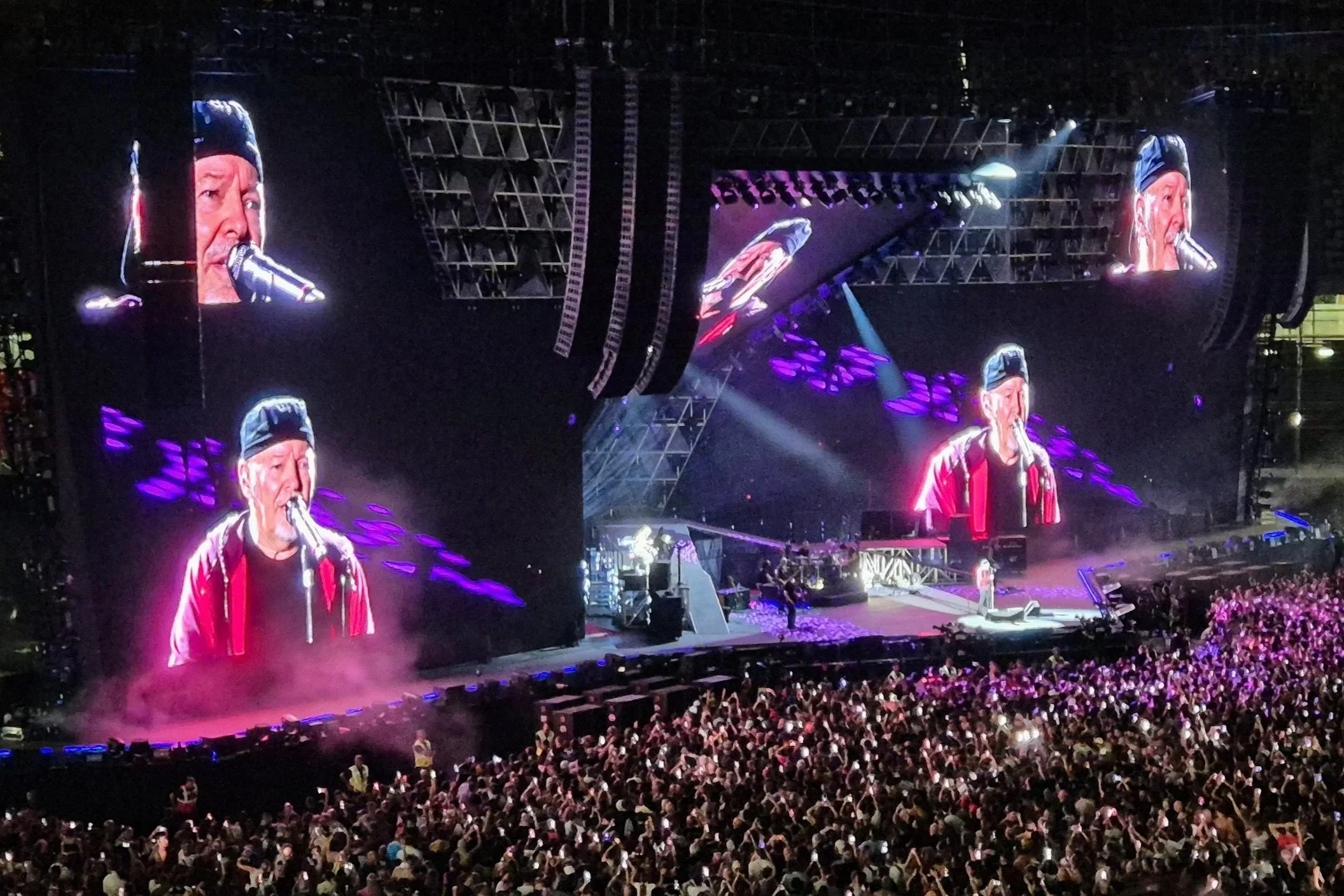Vasco Rossi singing on the stage and his image reflected on four big screens above the stage