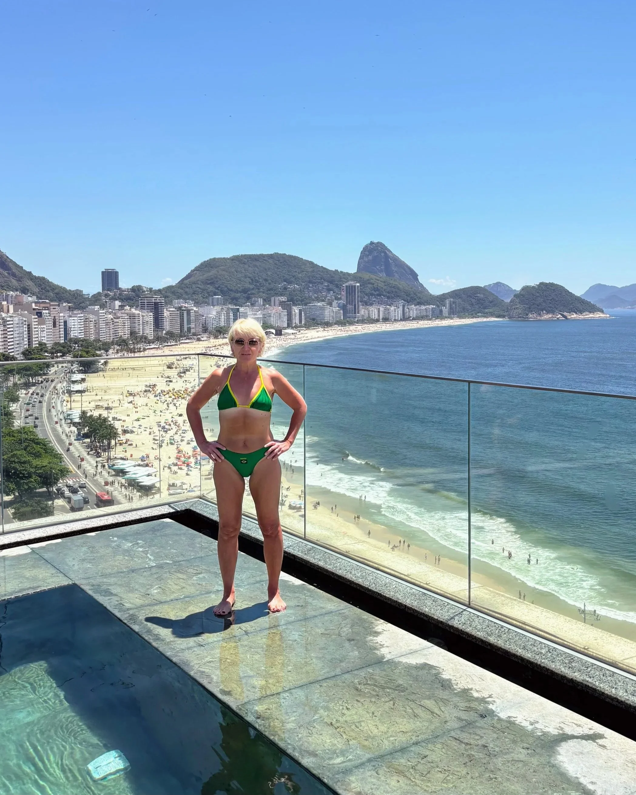 Anita at Miramar by Windsor Copacabana hotel pool, wearing a green and yellow Brazil bikini and Sugarloaf Mountain in the background