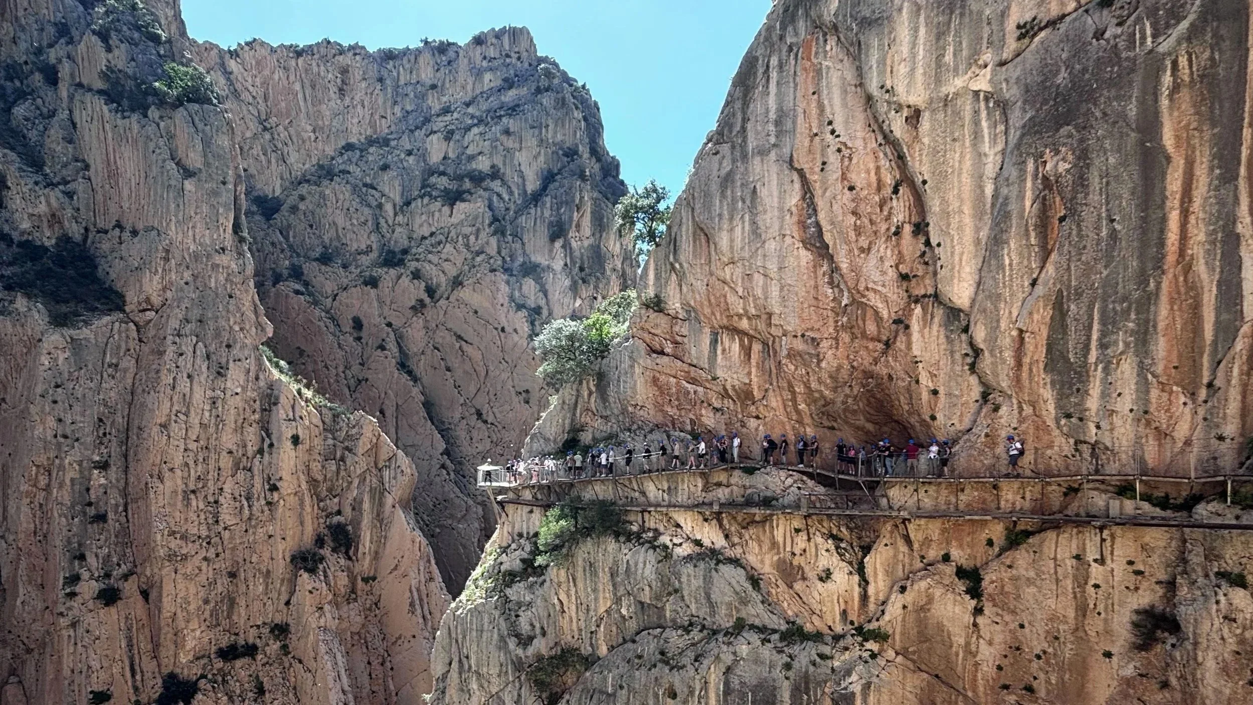 A group of hikers on the wooden walkway suspended on a rock in Caminito del Rey Spain