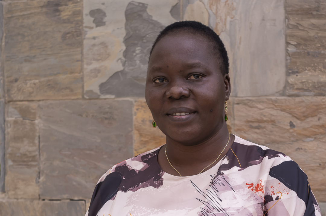A profile photo of Jackline Nasiwa standing in front of a stone wall 