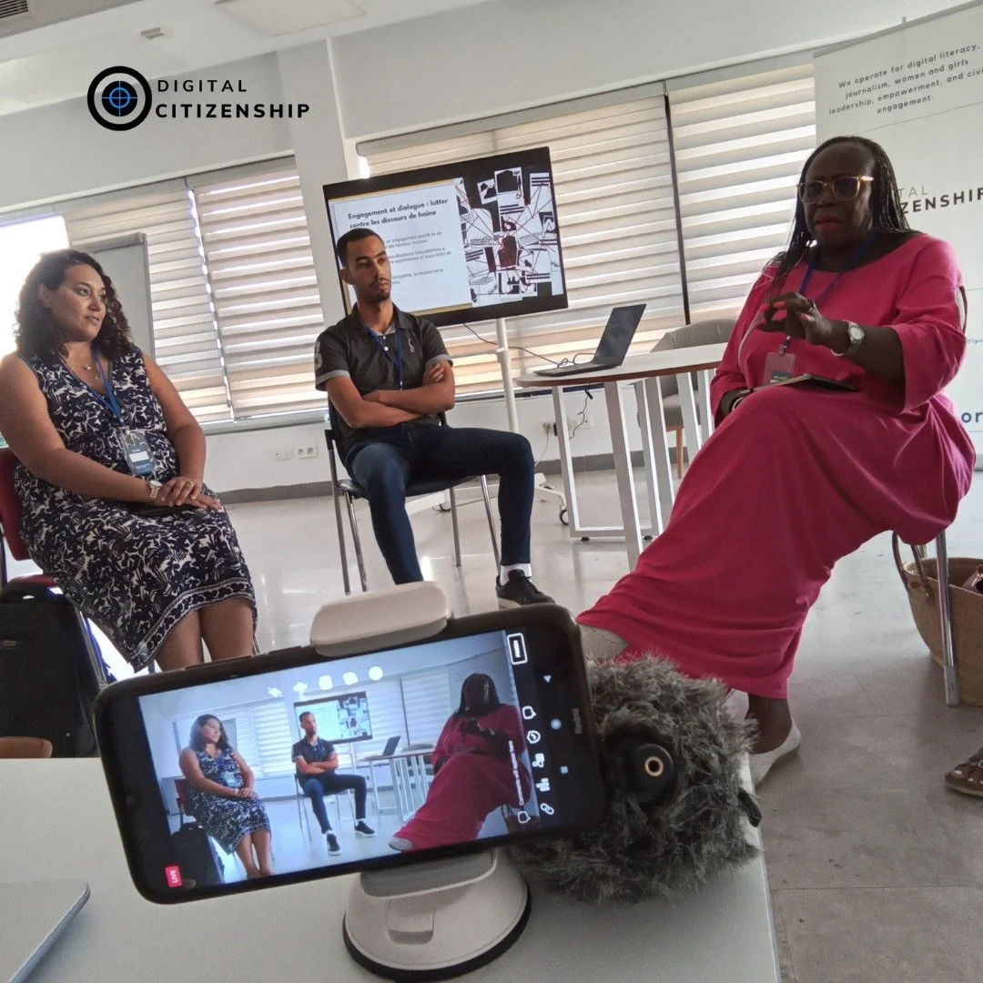 A panel of three people give a talk while a smartphone in the foreground records them
