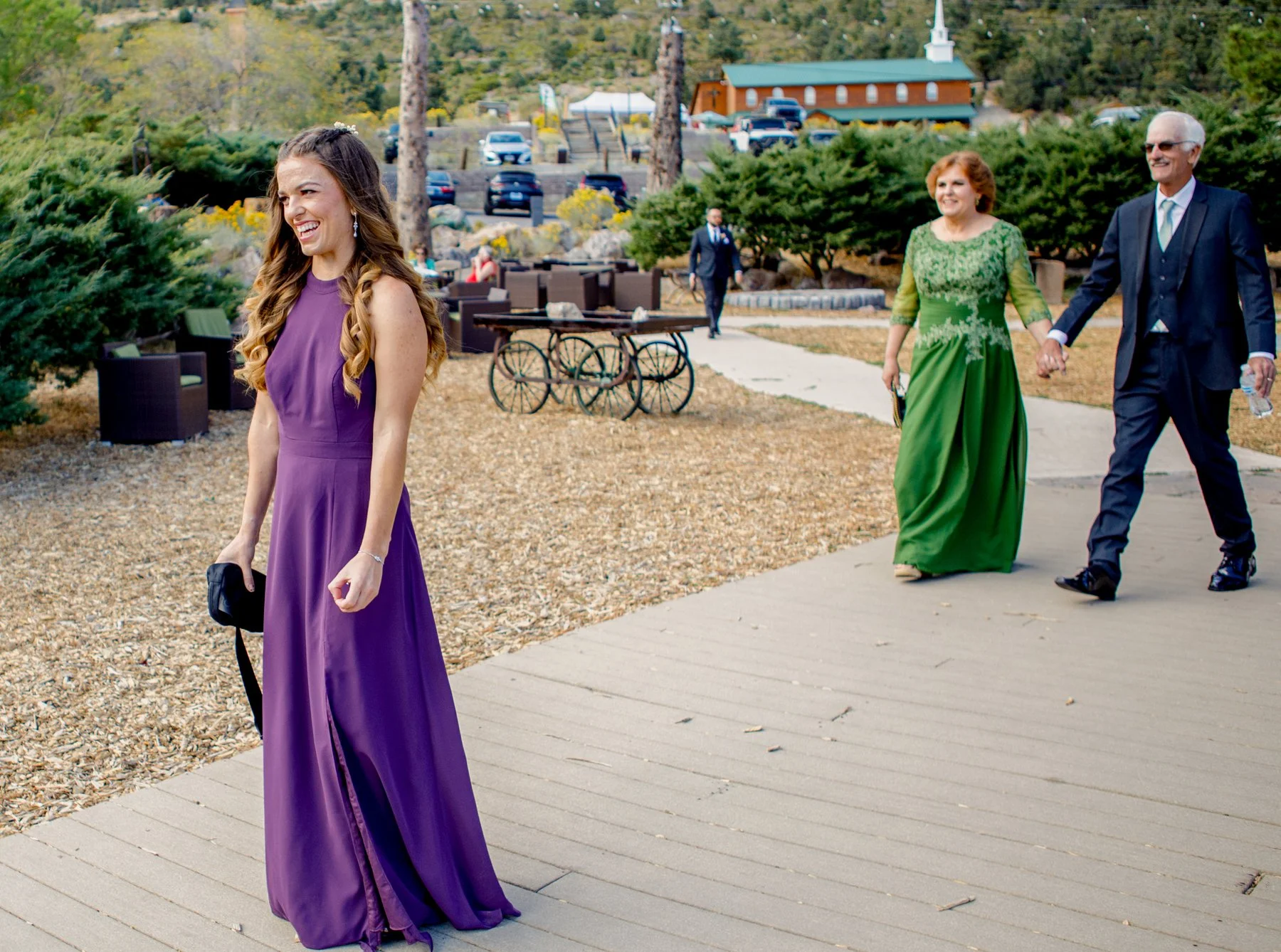 Bridesmaid and sister of the groom is approaching him for a first look, smiling at him as he turns around. Their parents are walking behind her.