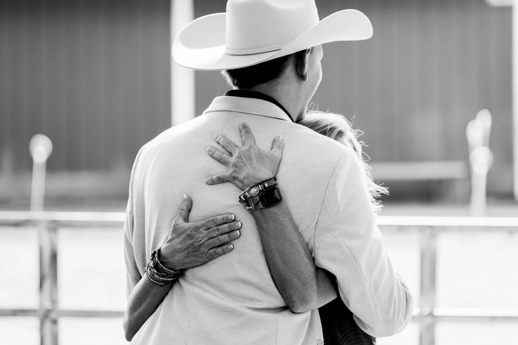 The back of the groom is shown with the hands of his mother hugging him.