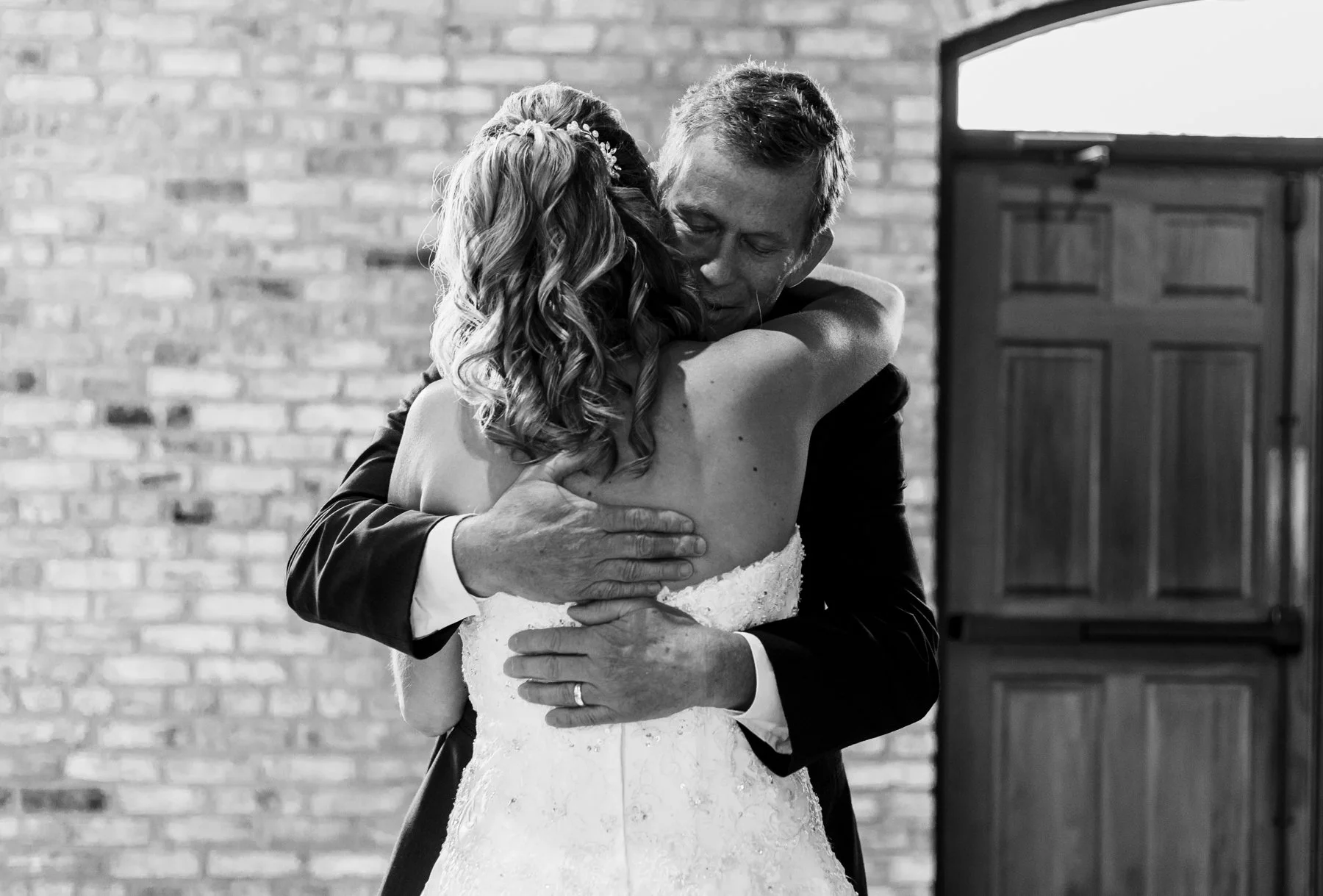 The father of the bride hugs her after seeing her in her wedding dress for the first time.