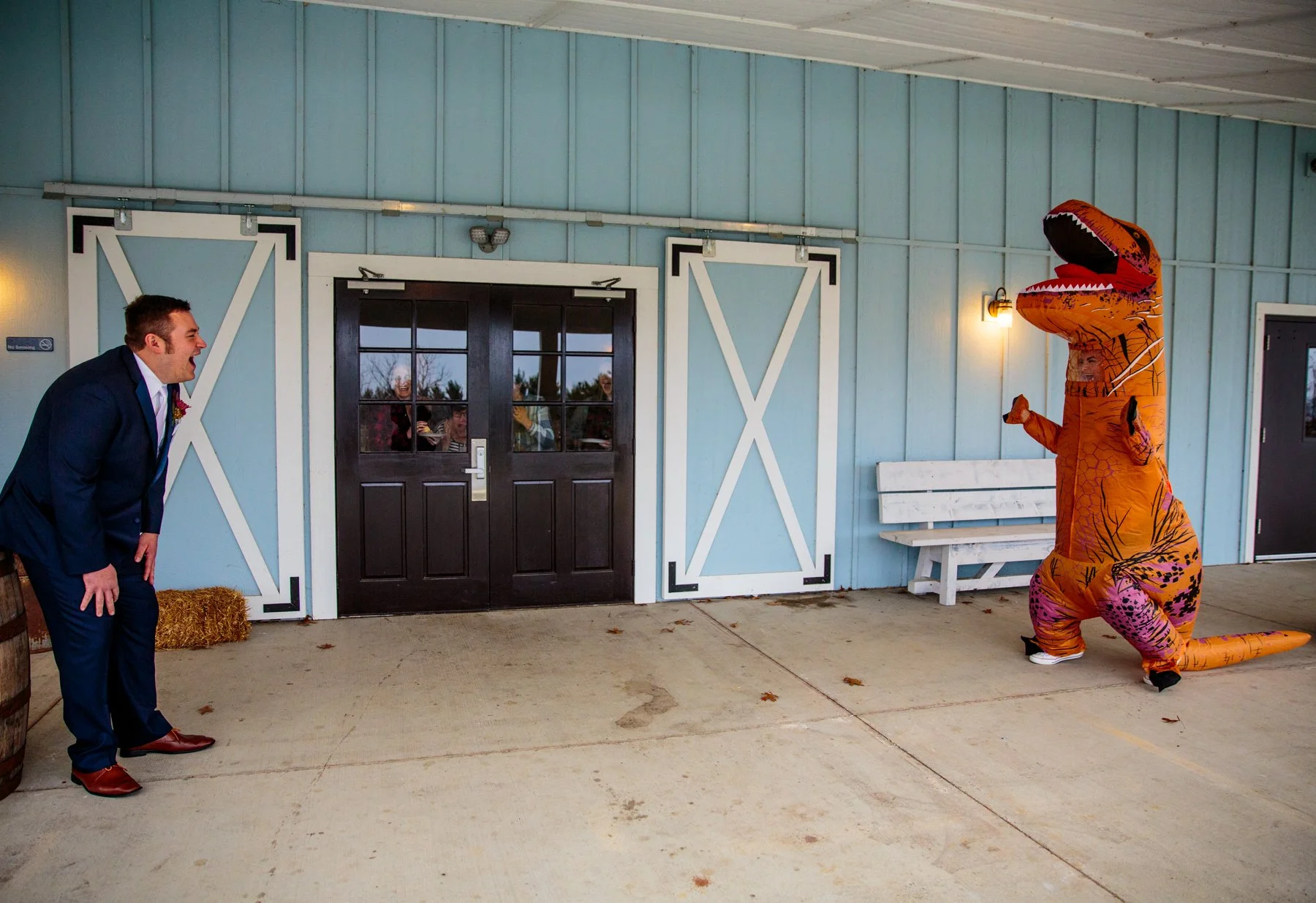 For their first look, the bride dressed up as a dinosaur in an orange inflatable dino suit. She is shown running to her husband who is bent over laughing.