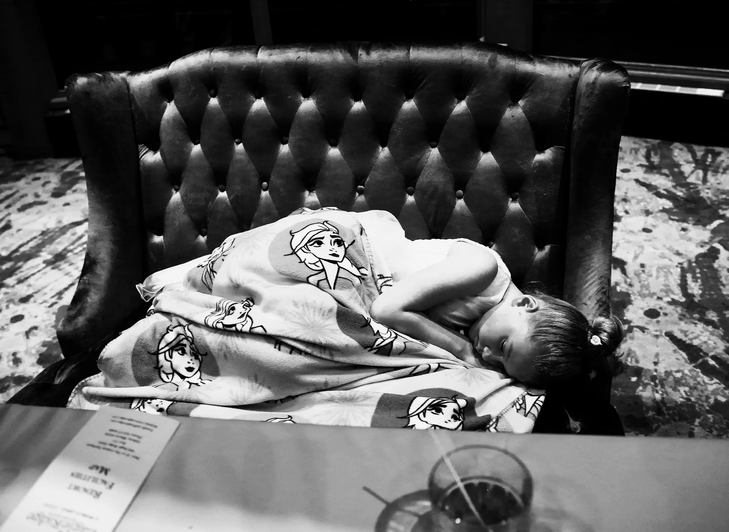 Child asleep under blanket on chair during wedding reception, candid moment showing how kids rest at weddings