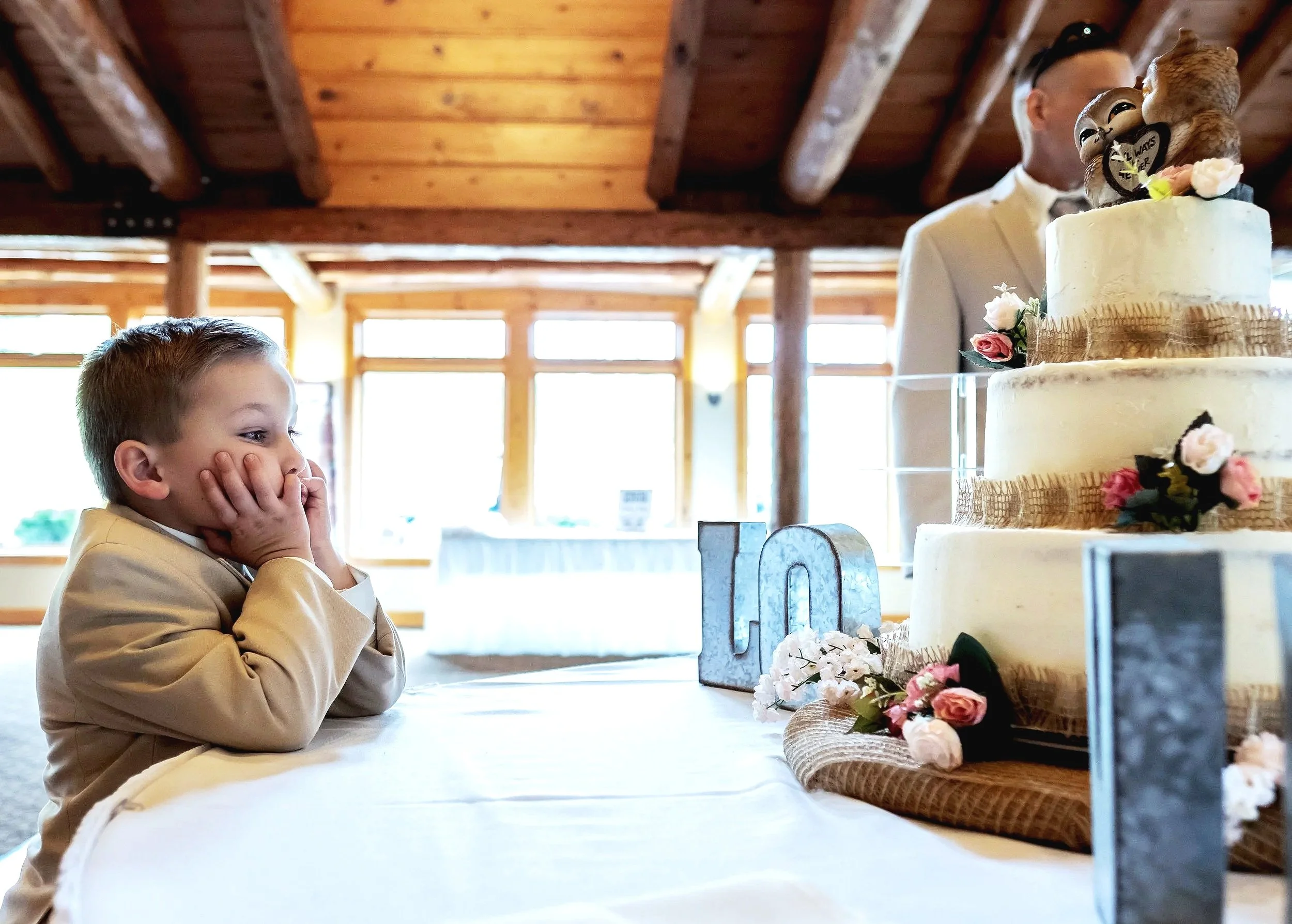 Young boy staring at wedding cake during reception, candid moment capturing kids’ reactions at weddings