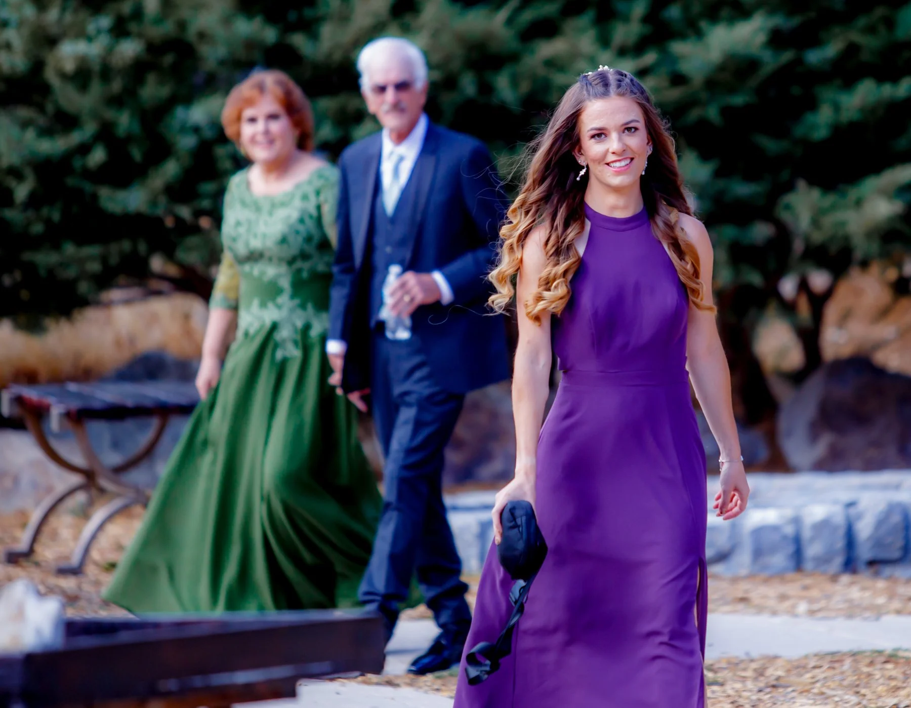 Bridesmaid and sister of the groom is approaching him for a first look. Their parents are walking behind her.