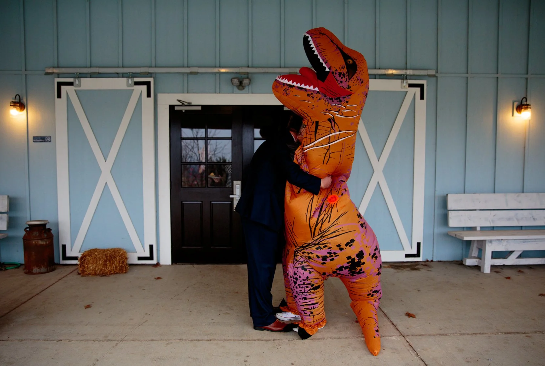 For their first look, the bride dressed up as a dinosaur in an orange inflatable dino suit. She and her husband share a hug after she surprised him during the first look.
