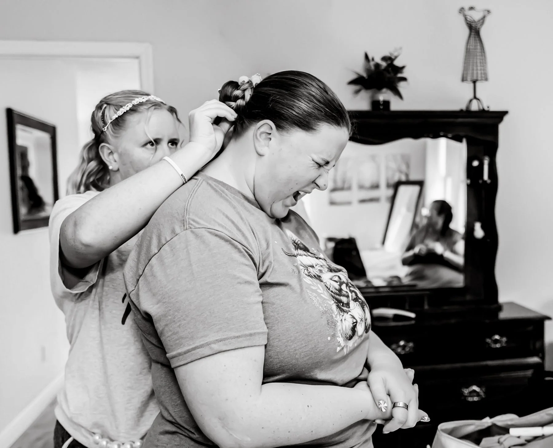 Bride is pinning the maid of honors hair.
