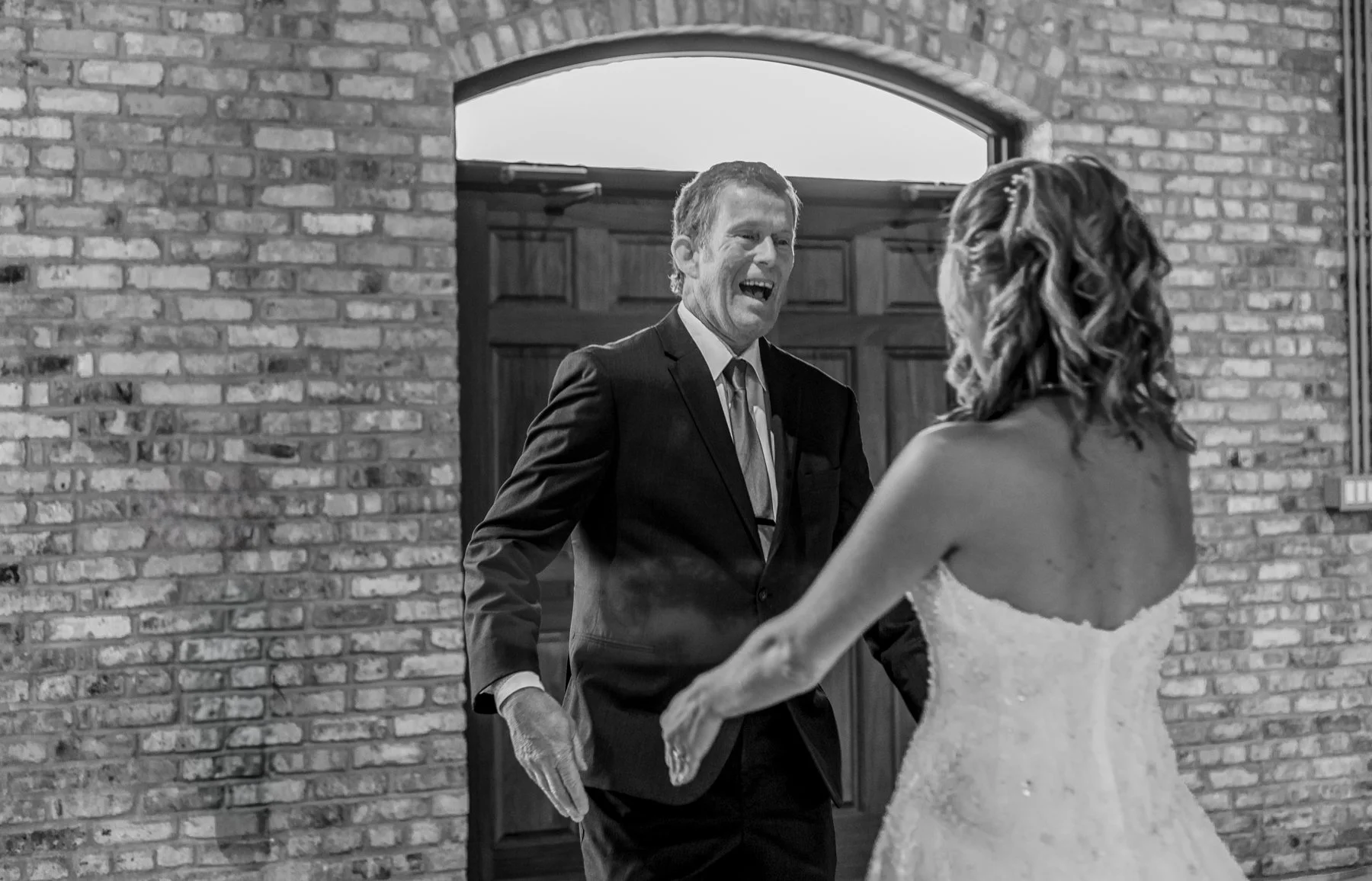 After turning around to see his daughter for the first time in her wedding dress, a father looks at her with a big look of surprise and happiness.