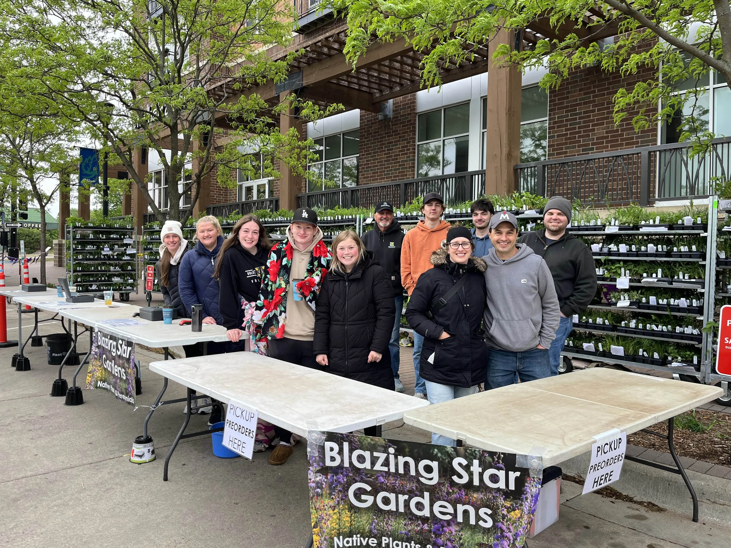 Metal racks of native plant pre-orders at a Twin Cities, Minnesota plant sale in a city street with people buying plants