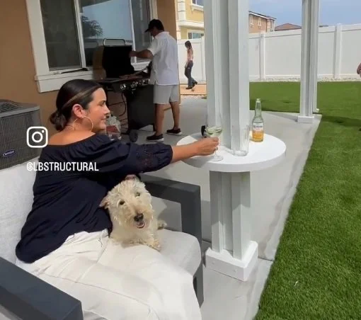 Woman using her AlumaTable to rest her drink, showcasing its practicality for patio spaces
