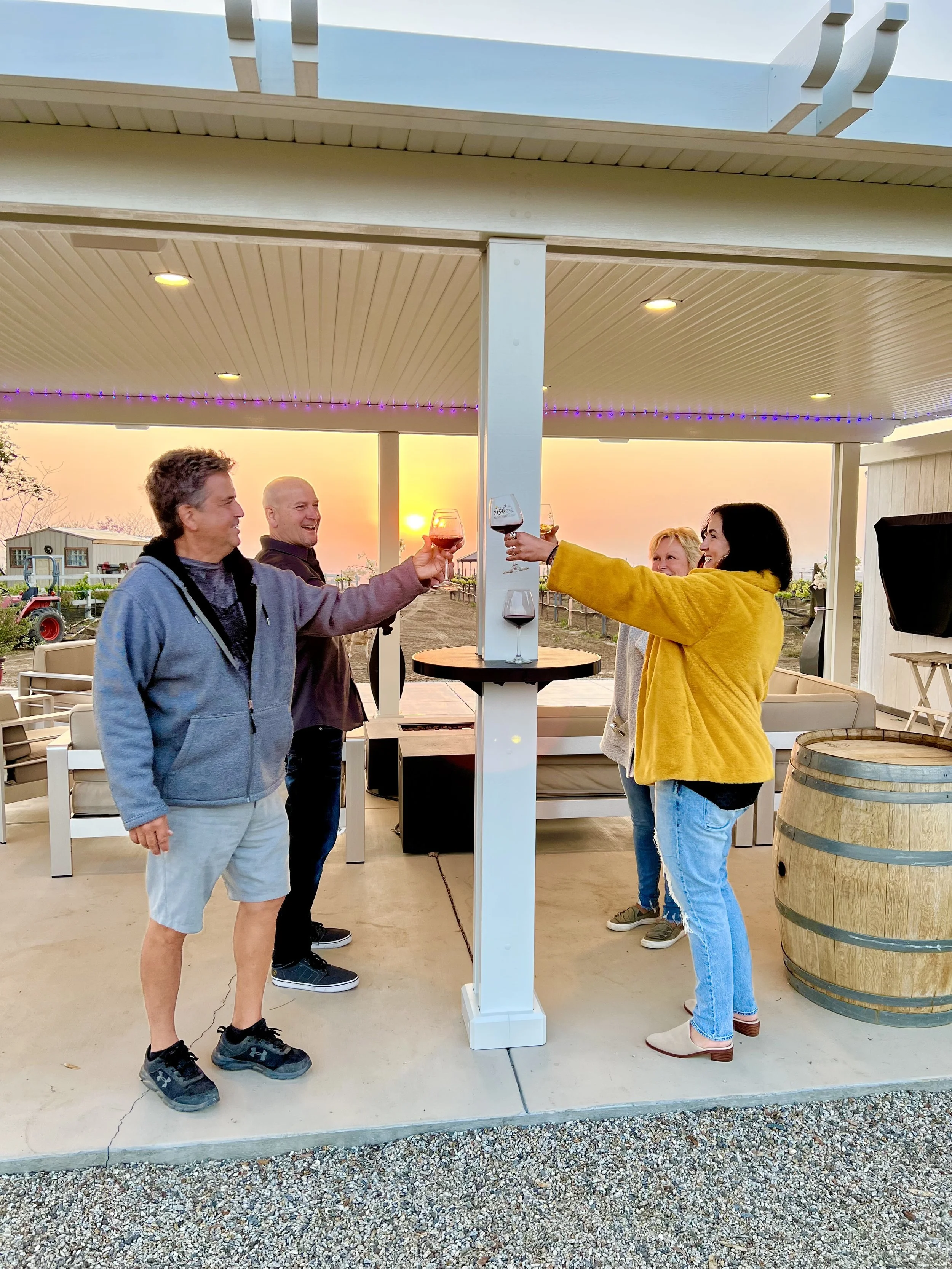 Two smiling couples toasting drinks with an Alumatable post table