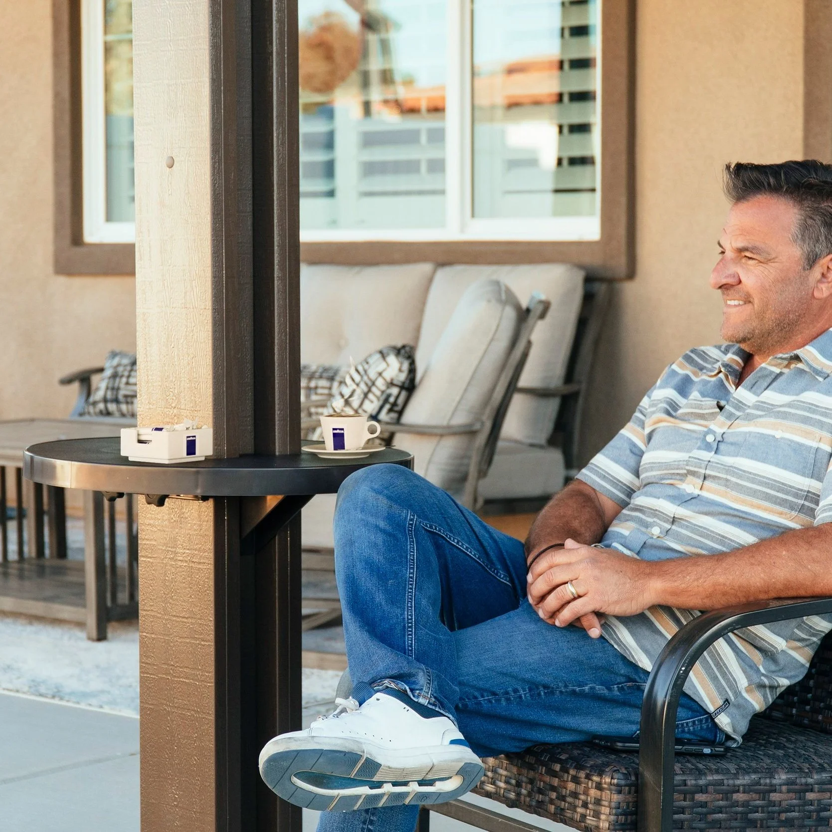 Smiling man sitting on a chair enjoying a drink with his new AlumaTable
