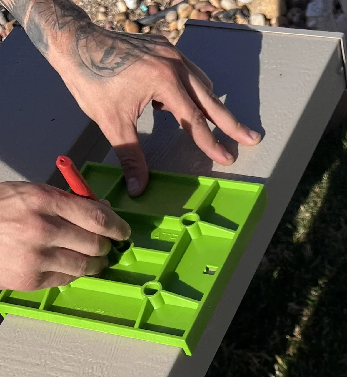 Person using the sideplate jig to line up screw holes for a patio installation