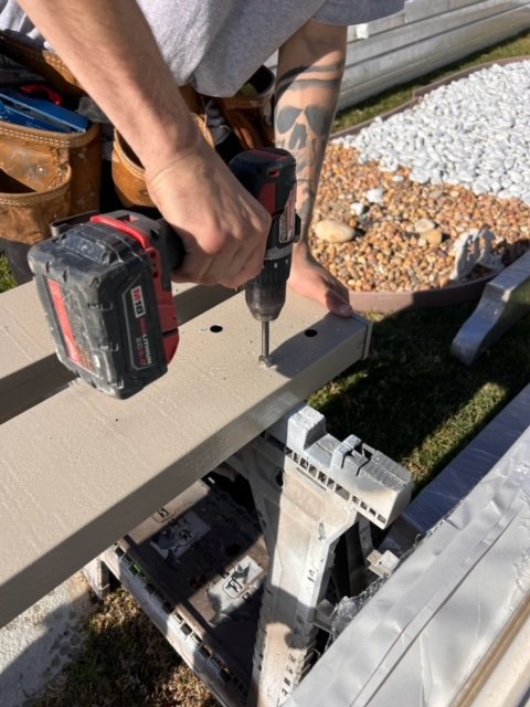 Person cutting marked center holes on a patio cover sideplate for an installation project