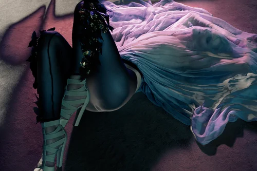A conceptual still life photograph featuring a sculptural black form draped with flowing translucent fabrics in pink, purple, and teal, set against a mauve-toned background with dramatic directional lighting that creates soft shadows and highlights…