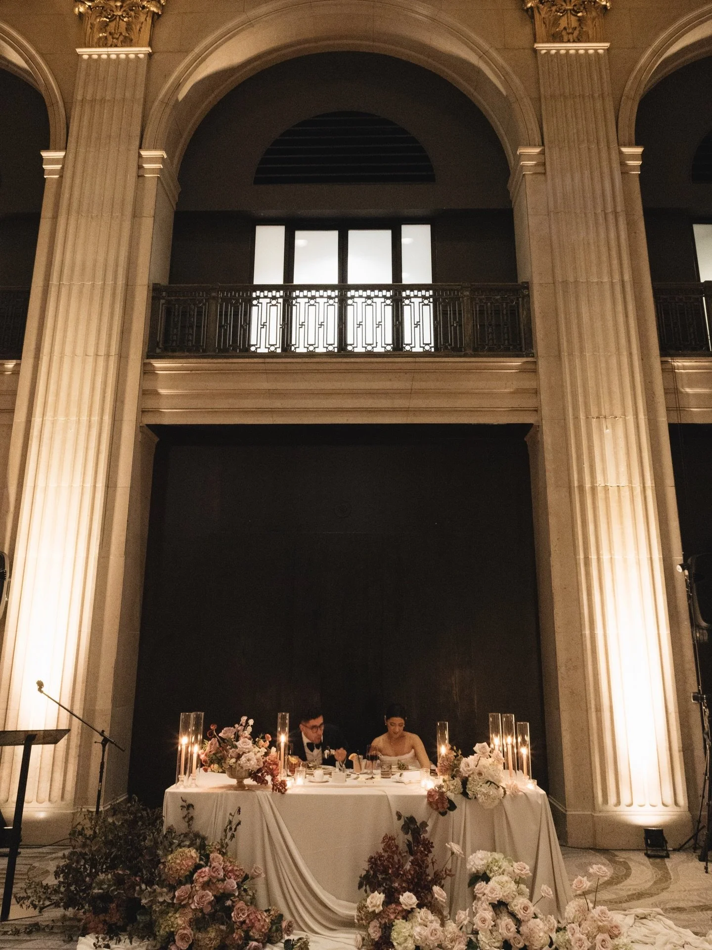 Like a Renaissance masterpiece come to life beneath towering marble columns and gilded ceilings, the bride and groom sit at their candlelit head table draped in cascading florals, as if painted by an old master 🖼️

The glow, the symmetry, the quiet 