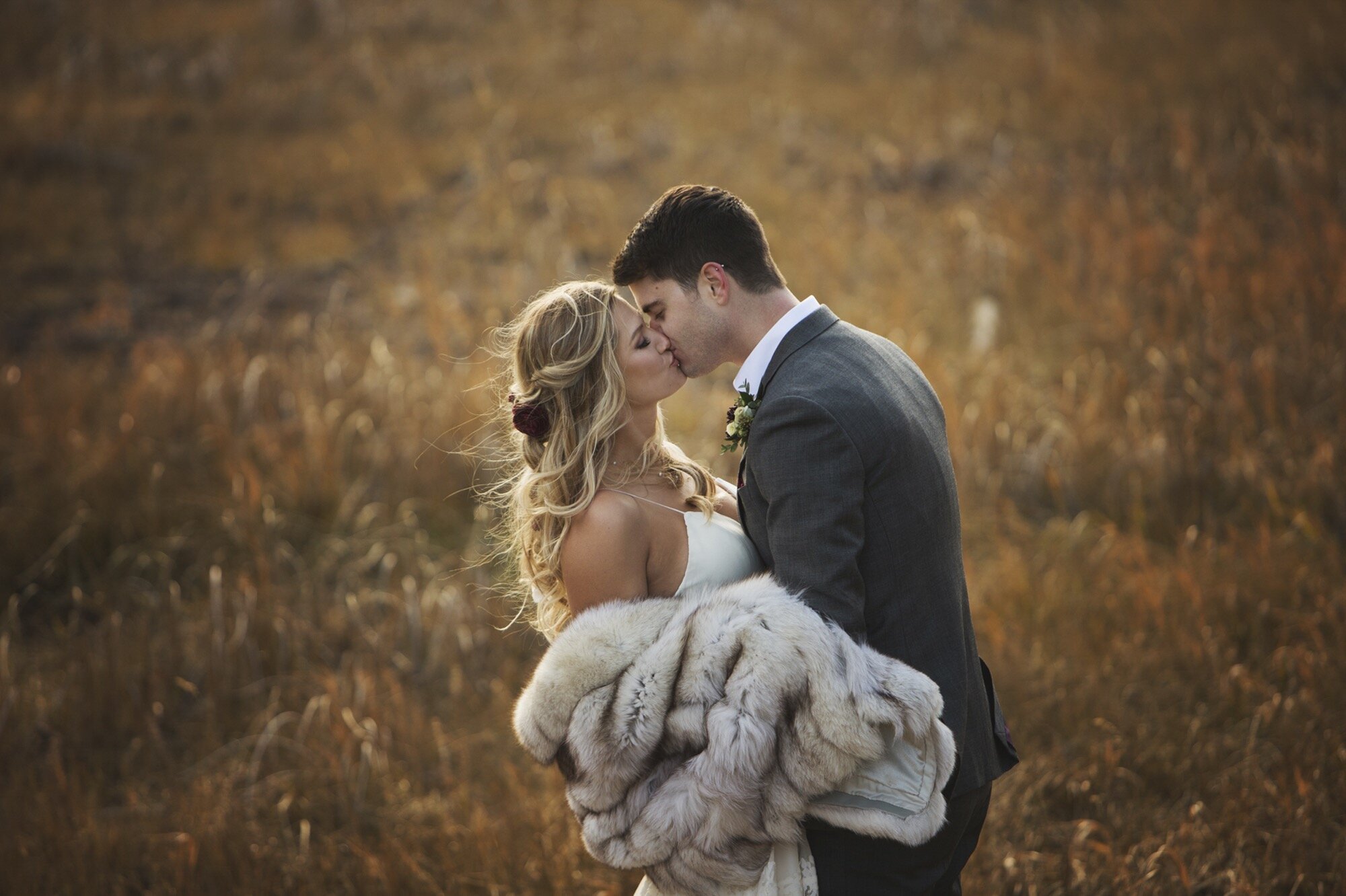 romantic kiss bride groom fall field canmore alberta.jpg