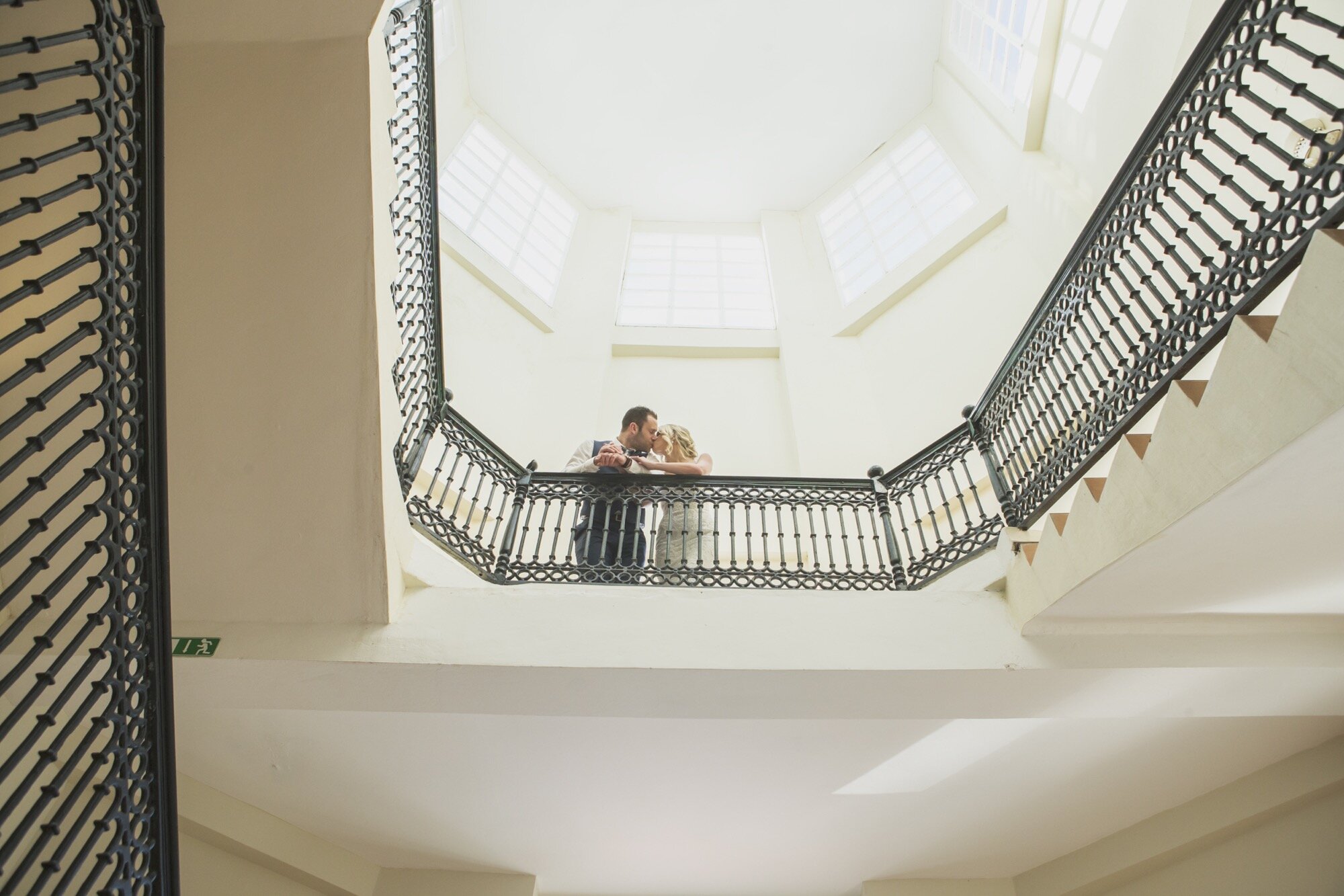 bride groom kissing white stylish editorial stairwell.jpg