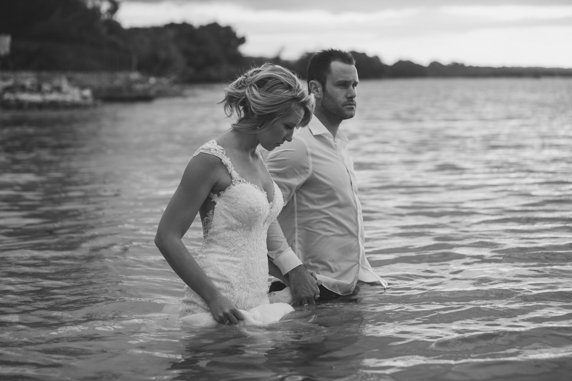 bride groom walking waist deep into ocean black and white.jpg