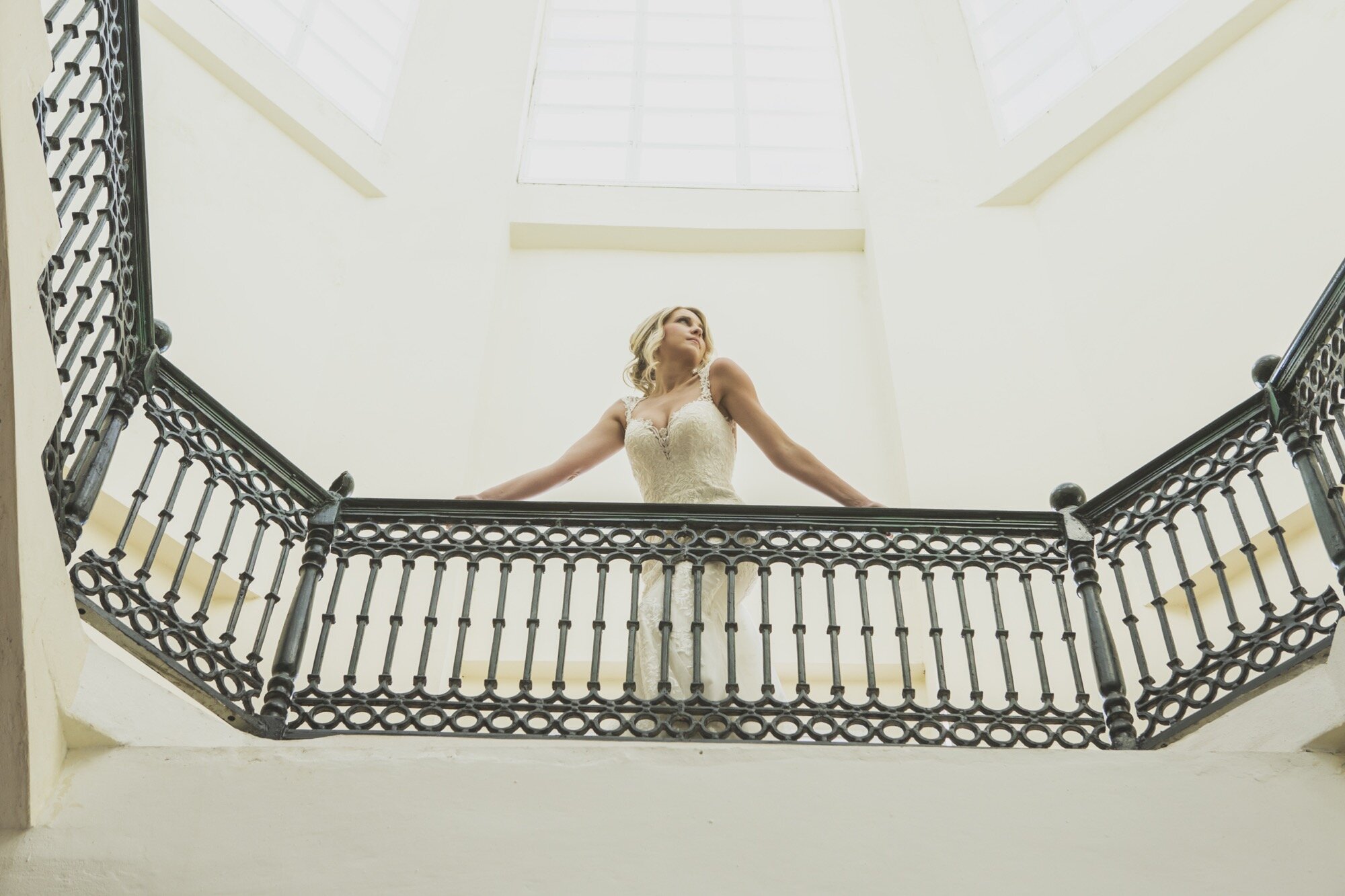 bride leaning on railing light filled staircase.jpg