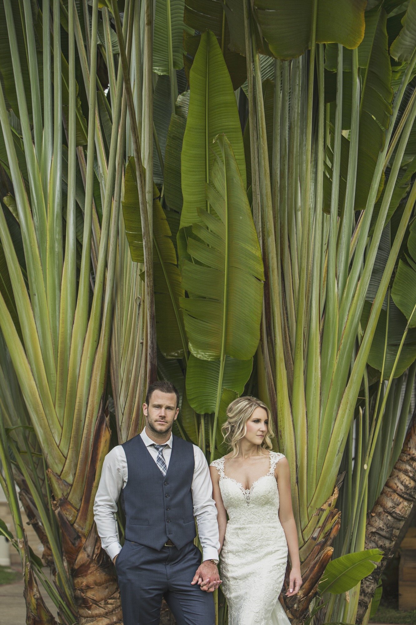 destination bride groom standing in front tropical tree.jpg