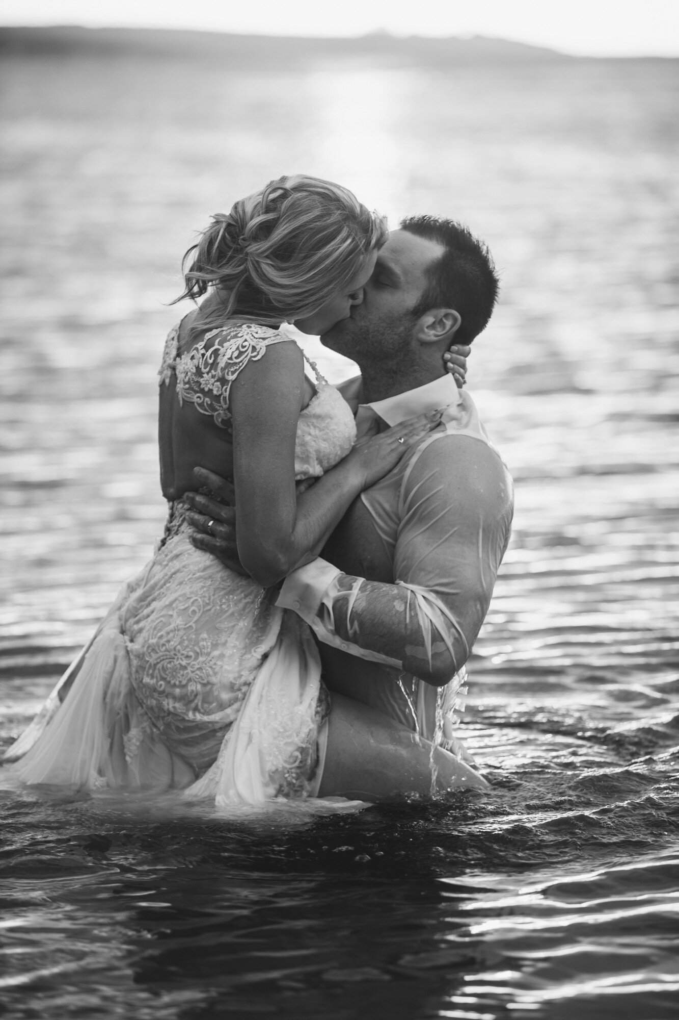 groom lifting bride for kiss in ocean black and white.jpg