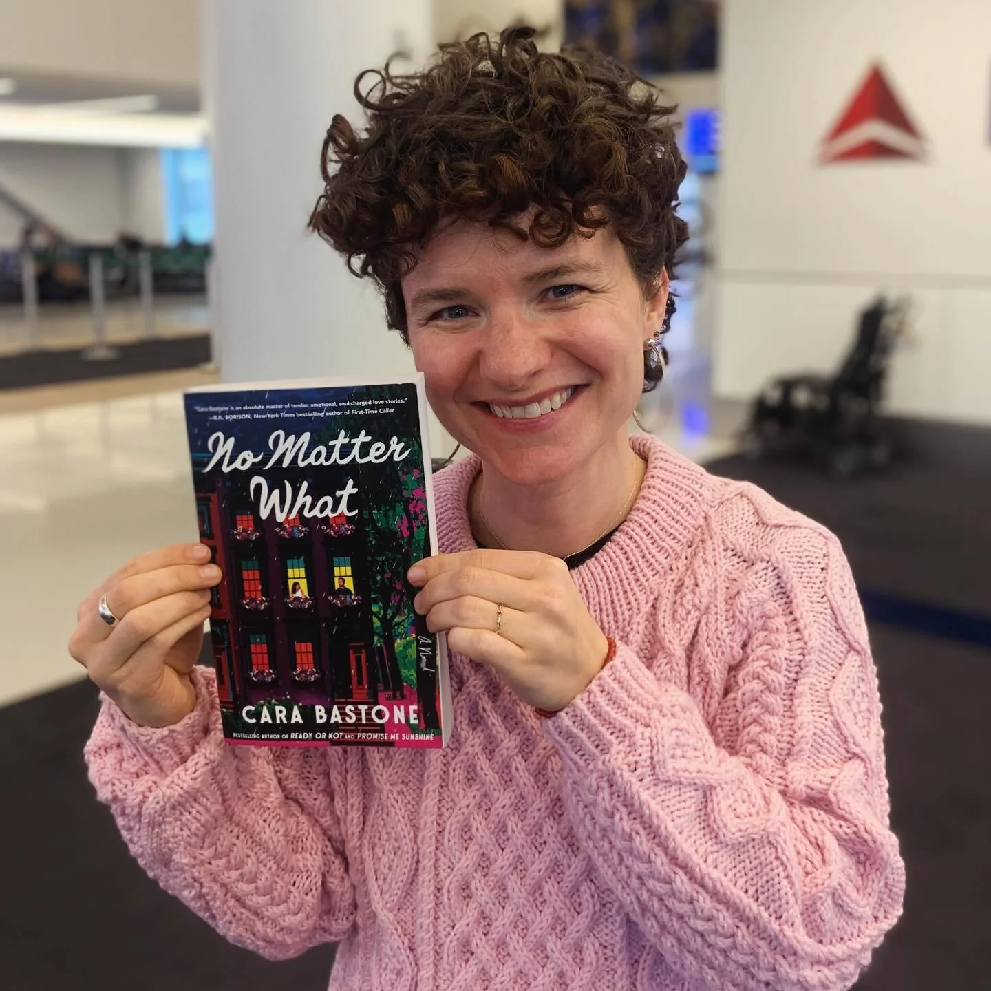 The book is No Matter What, the author is me, aged 37, at the airport on a book tour, the photo is taken by my flight attendant (hi Jessica!) and the sweater is knitted by my mom! There is a honeycomb of joy and pride and excitement within me. Can yo
