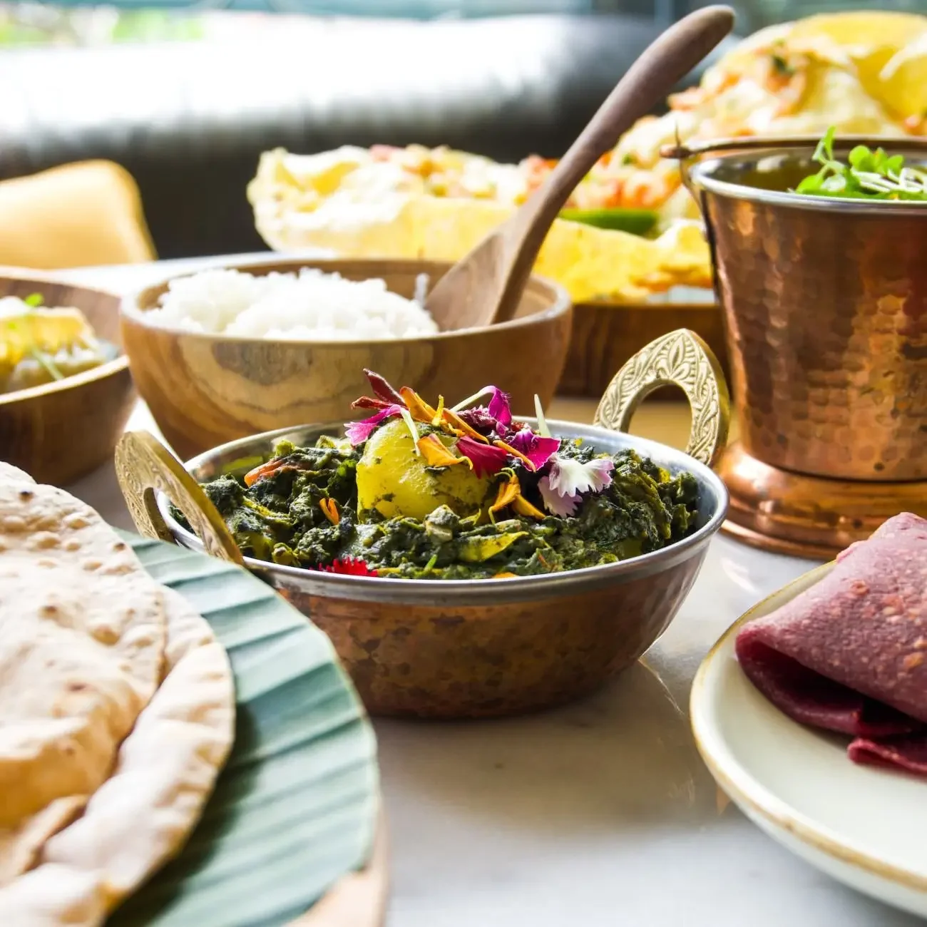 Saag Aloo, a traditional Indian dish with potatoes and spinach in a rich, spiced green sauce, served in a copper bowl at Pesona Lounge Ubud.