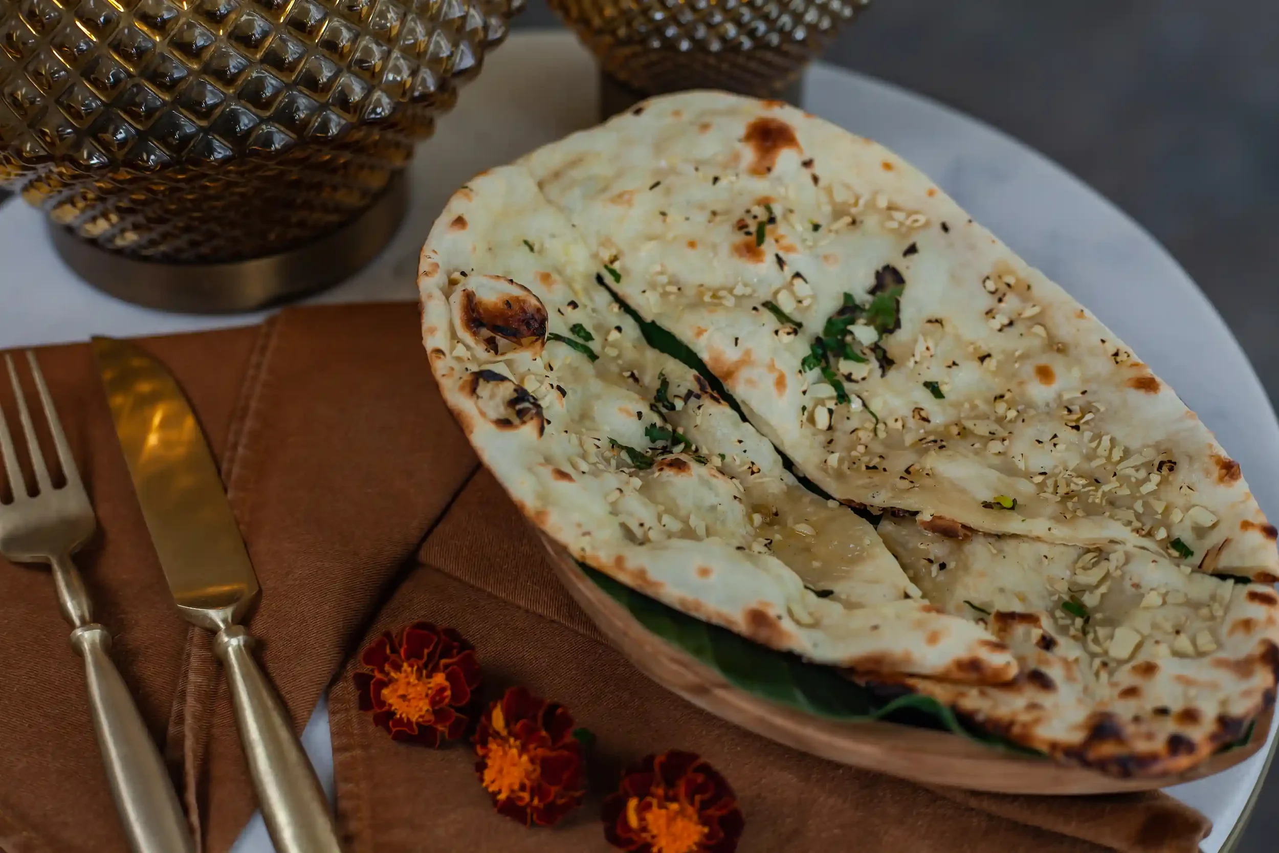 Image Alt Text:  Freshly baked garlic naan topped with chopped garlic and herbs, served on a plate at Pesona Lounge Ubud, an Indian restaurant in Bali.
