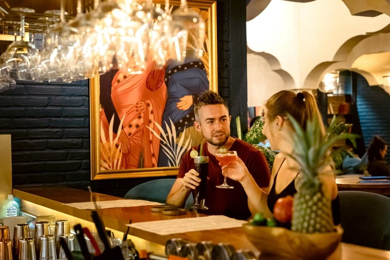 A couple sharing handcrafted cocktails during a romantic evening at Pesona Lounge Ubud.