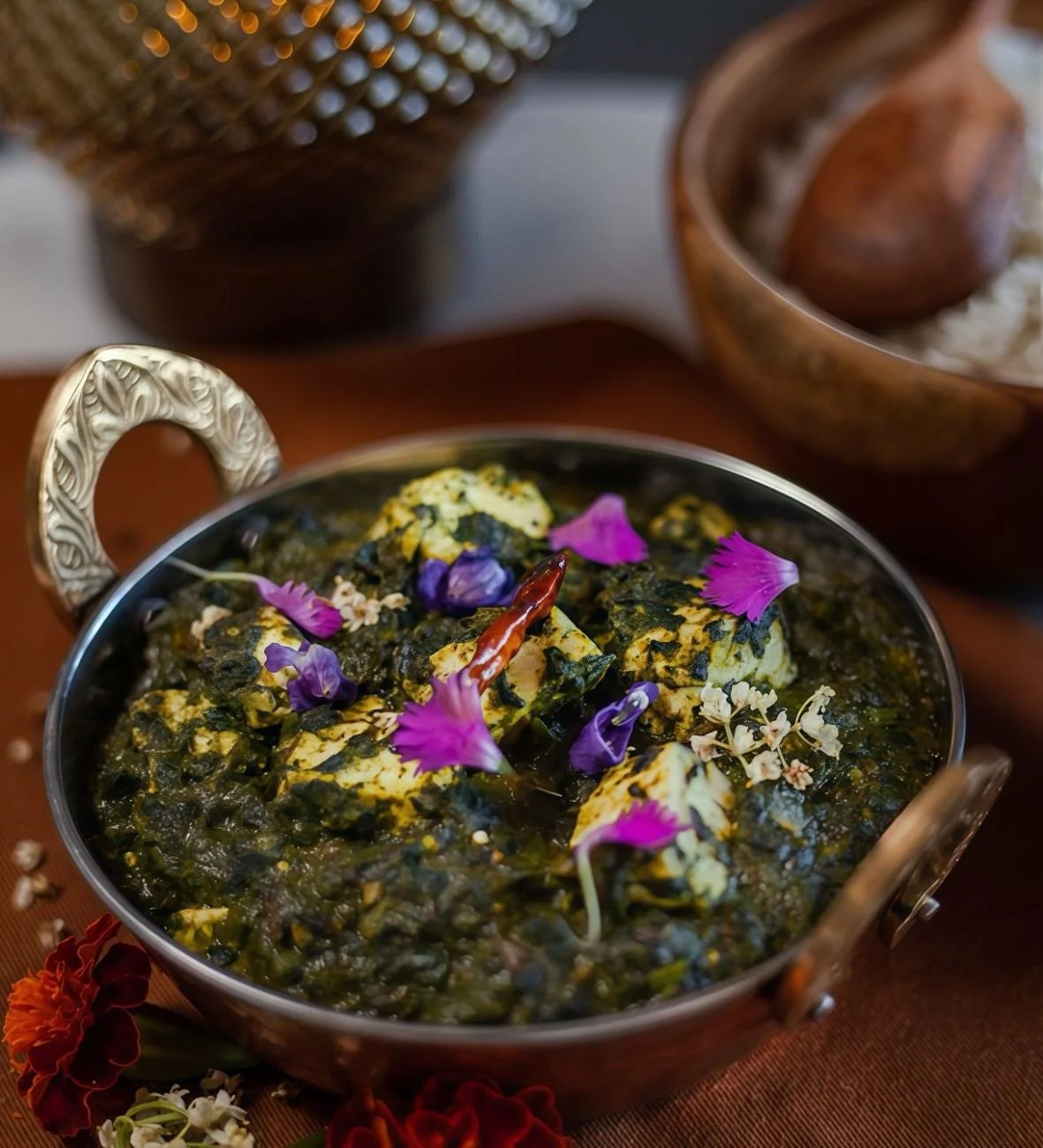 Saag paneer with pieces of paneer in leafy greens, topped with colourful flower petals at Pesona Lounge Ubud.